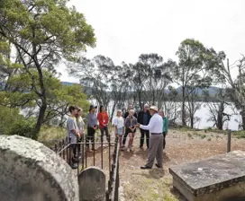 Tour guide with tourists around the graveyard of the Isle of the Dead - Port Arthur Historic Site.