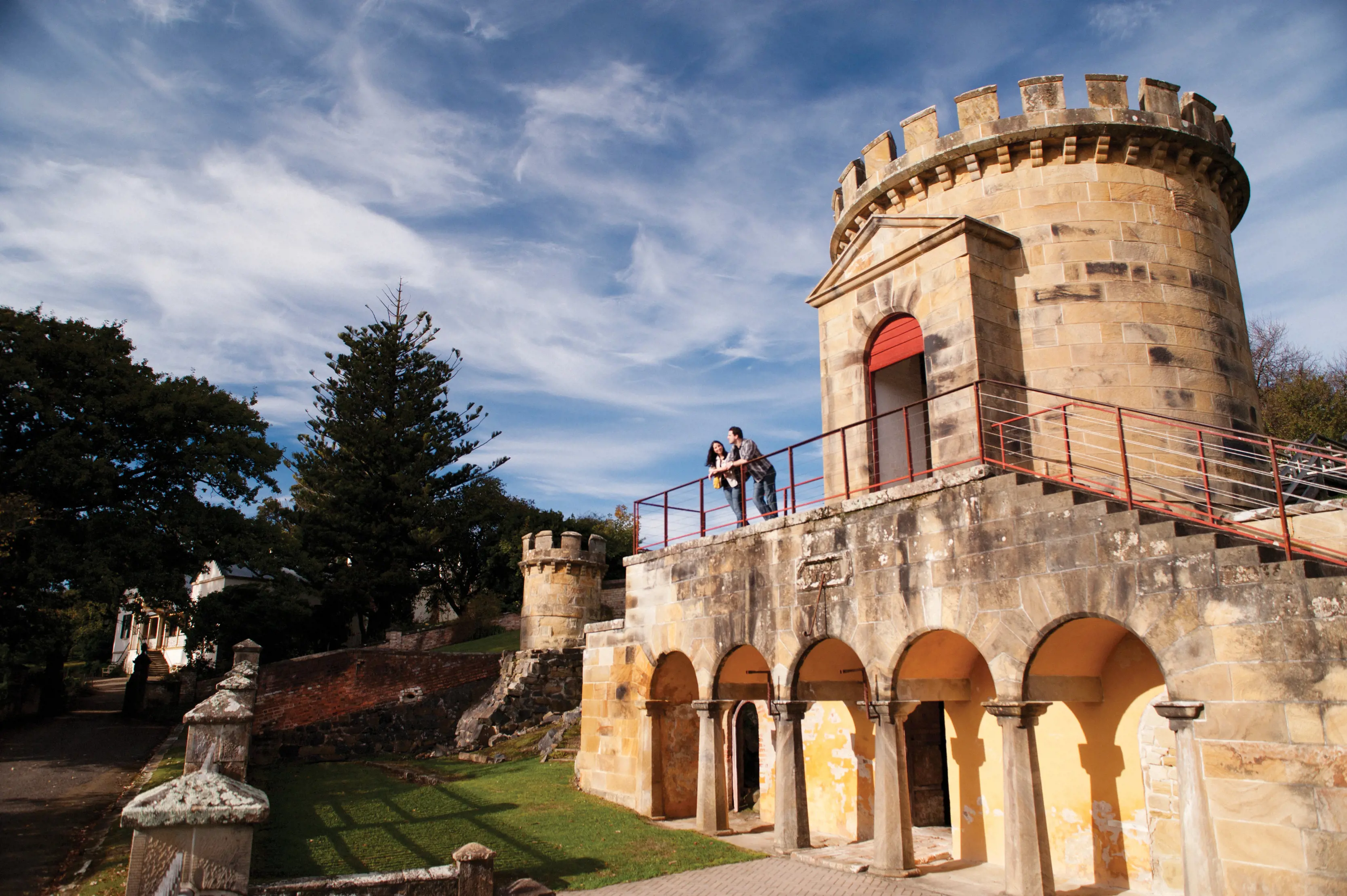 A couple resting on the railings at the top of the steps of the Guard Tower, Port Arthur Historic Site.