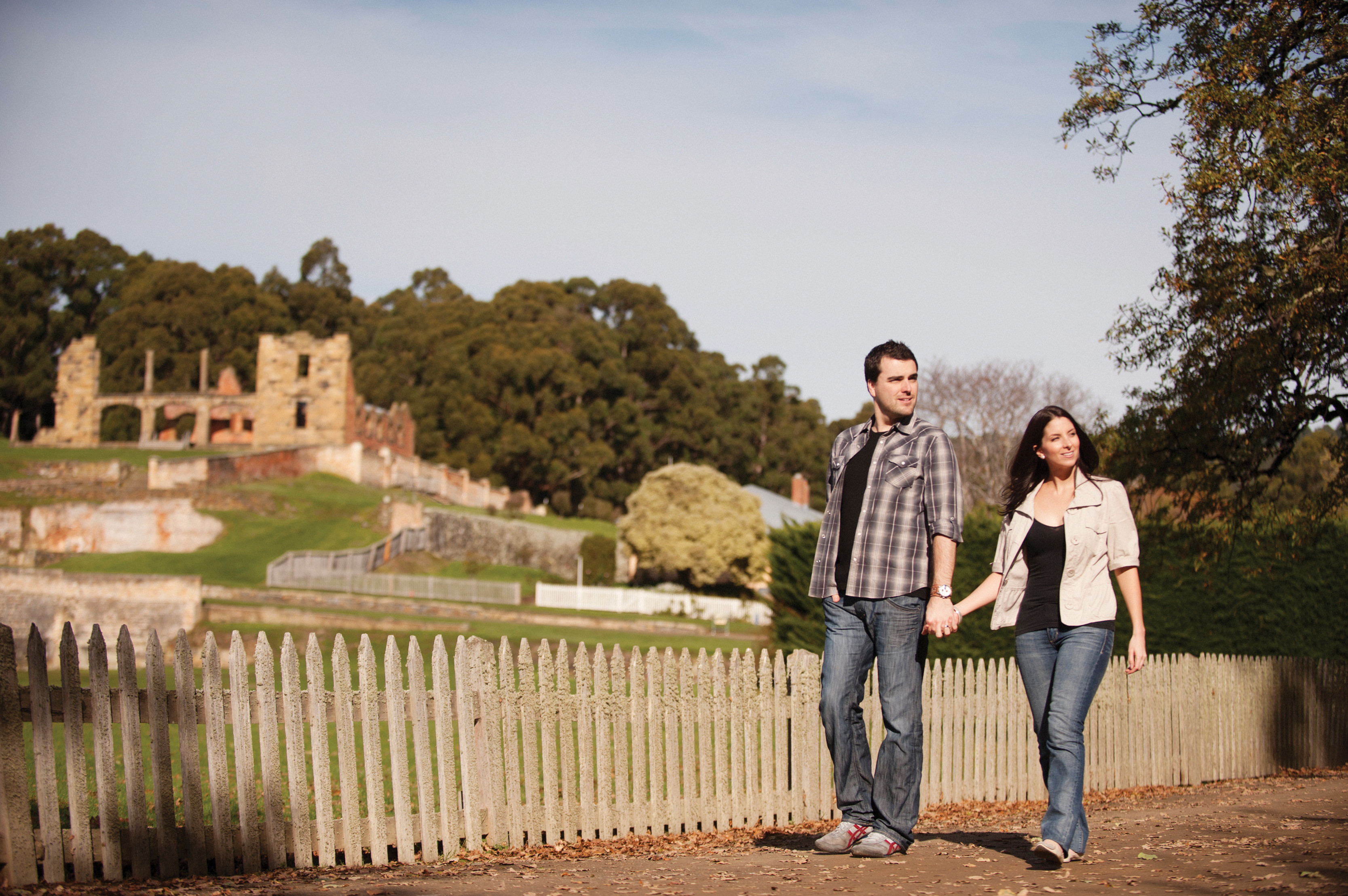 A couple holding hands walking past the hospital at Port Arthur Historic Site. 