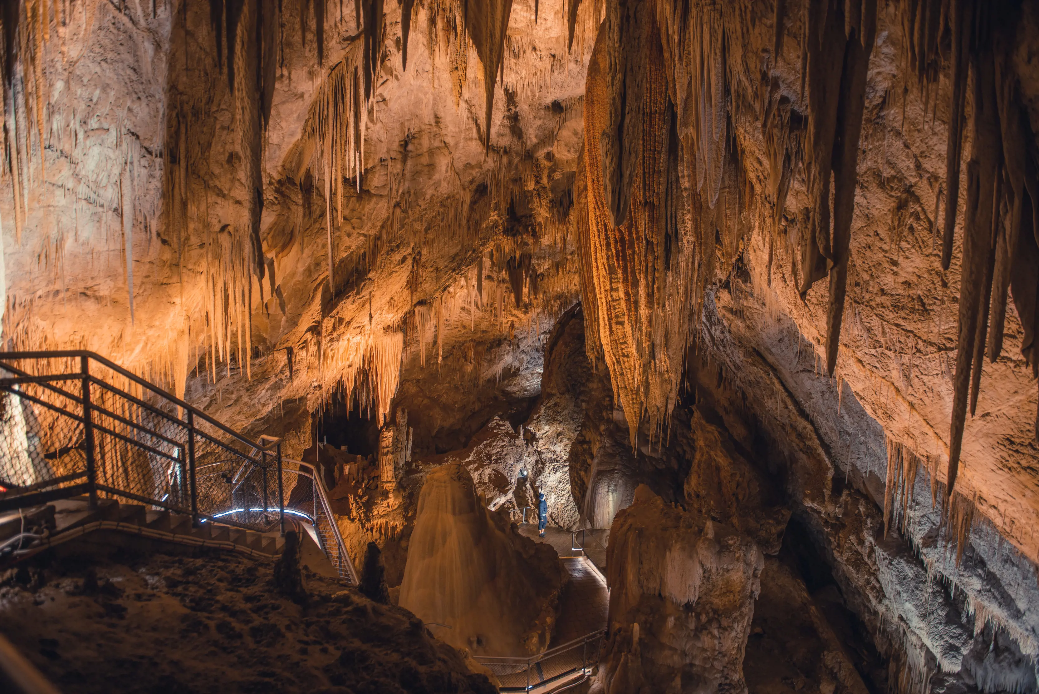 Looking into the depths of the Hastings dolomite Caves with a person walking a path further below.