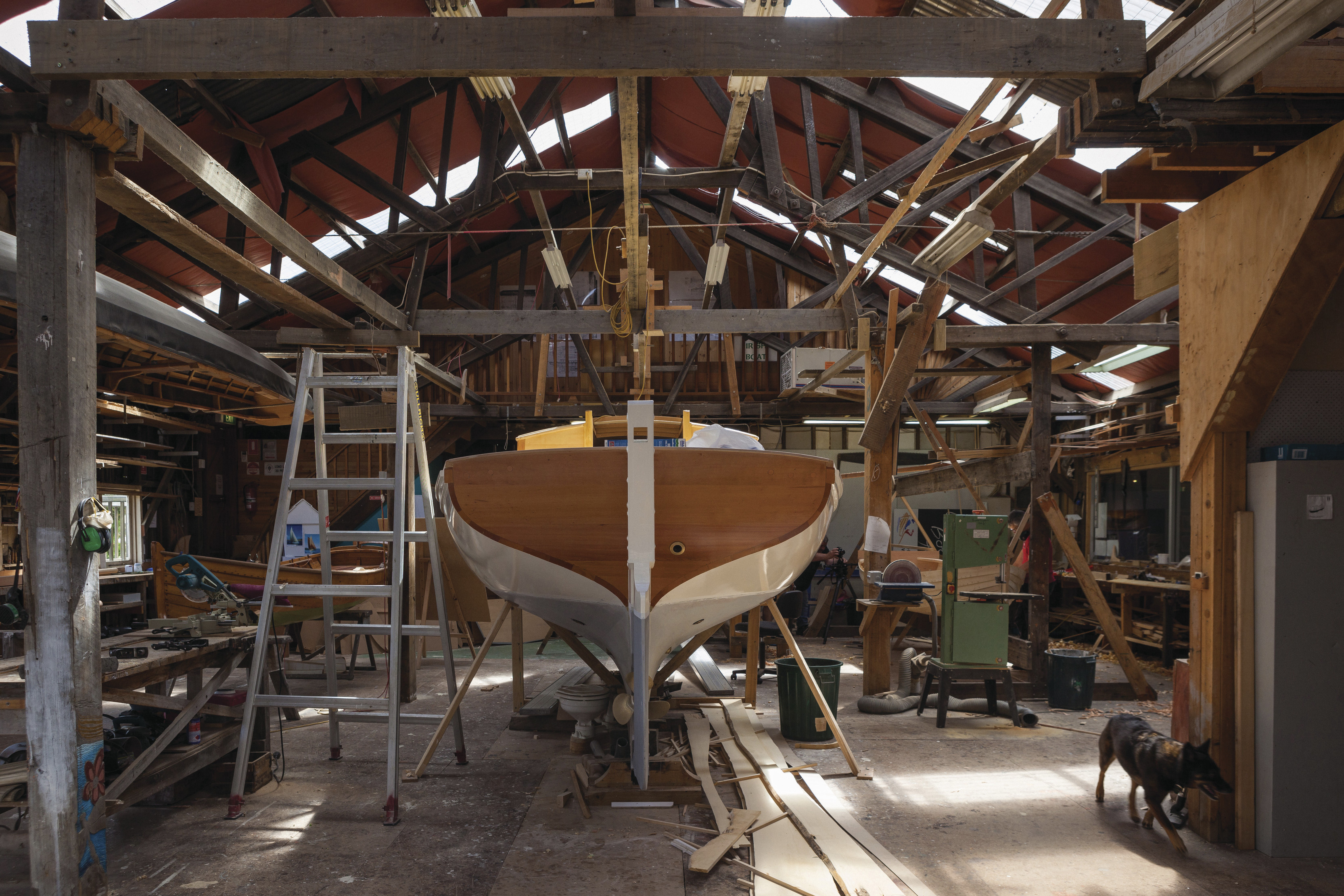 Beautiful wooden boat on boat stand in boat shed with a ladde3r next to it. Wooden Boat Centre Tasmania