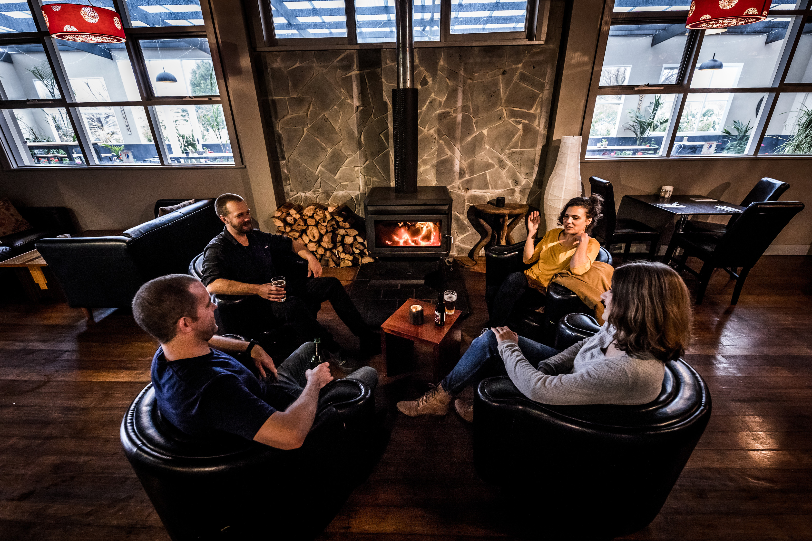 People laughing around a fireplace at Highlander Arms - Tarraleah Estate.