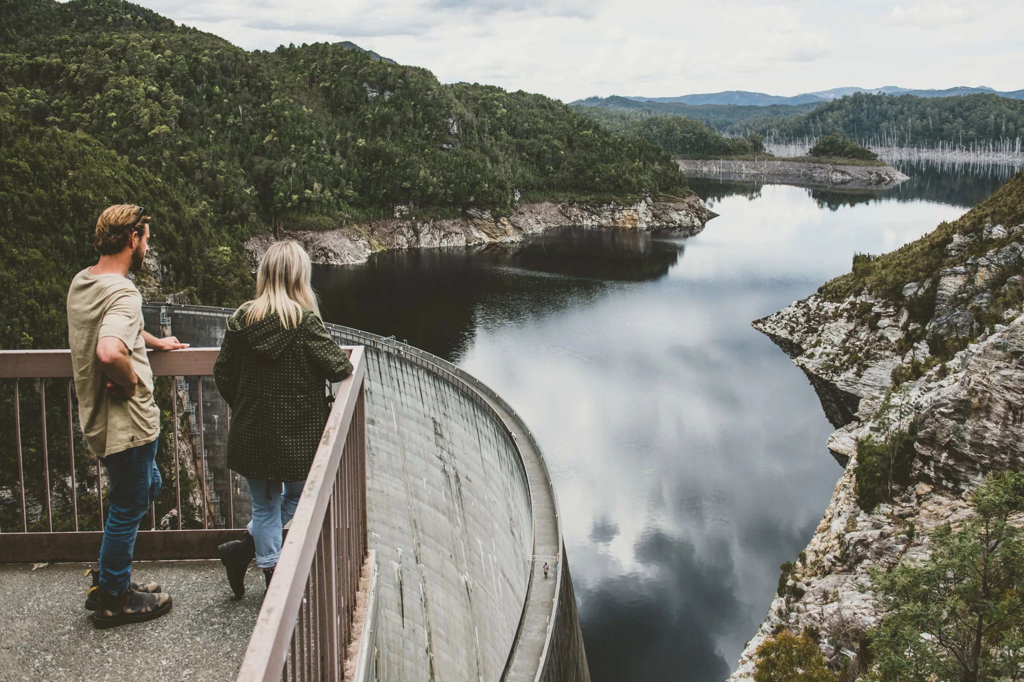 A couple stand at a look out at The Gordon Dam, a double curvature arch dam on the Gordon River.