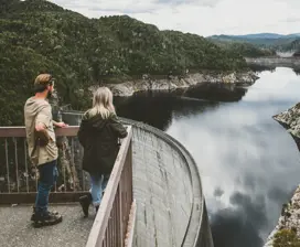A couple stand at a look out at The Gordon Dam, a double curvature arch dam on the Gordon River.
