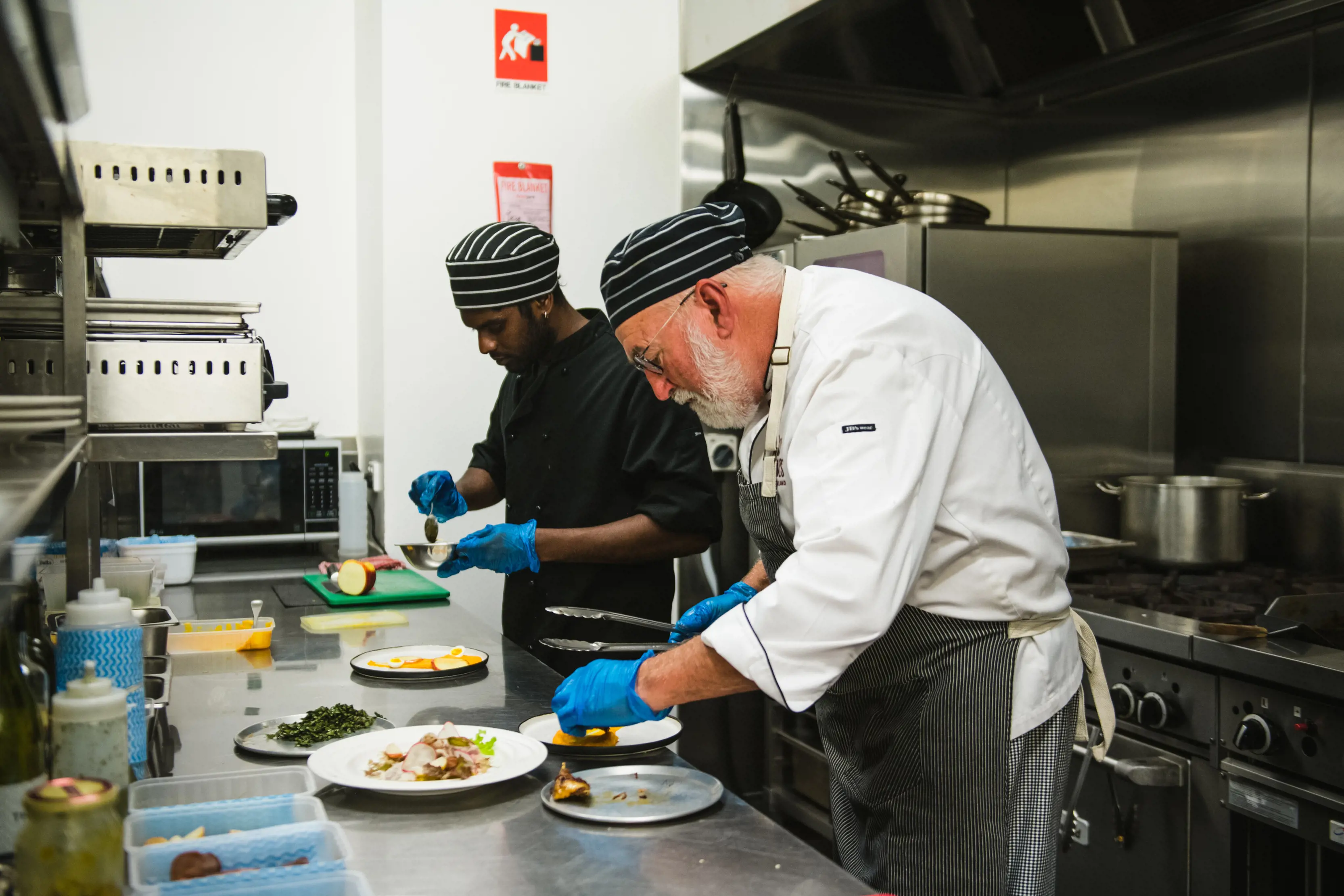 Two chefs in the kitchen, preparing food at the Wild Harvest Restaurant and Cooking School.