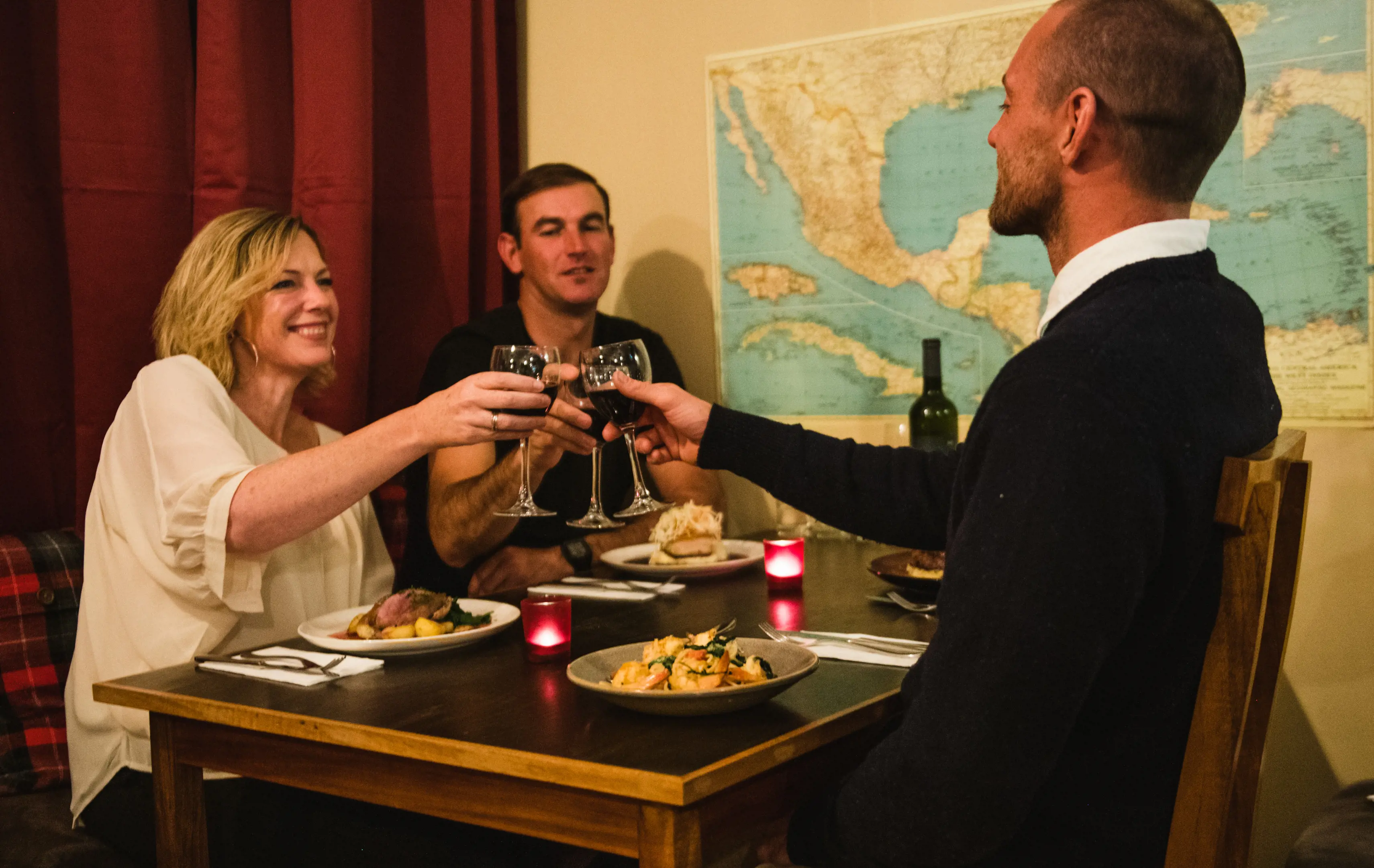 Three people holding a glass of wine, raising a toast, at the Oleada restaurant. 