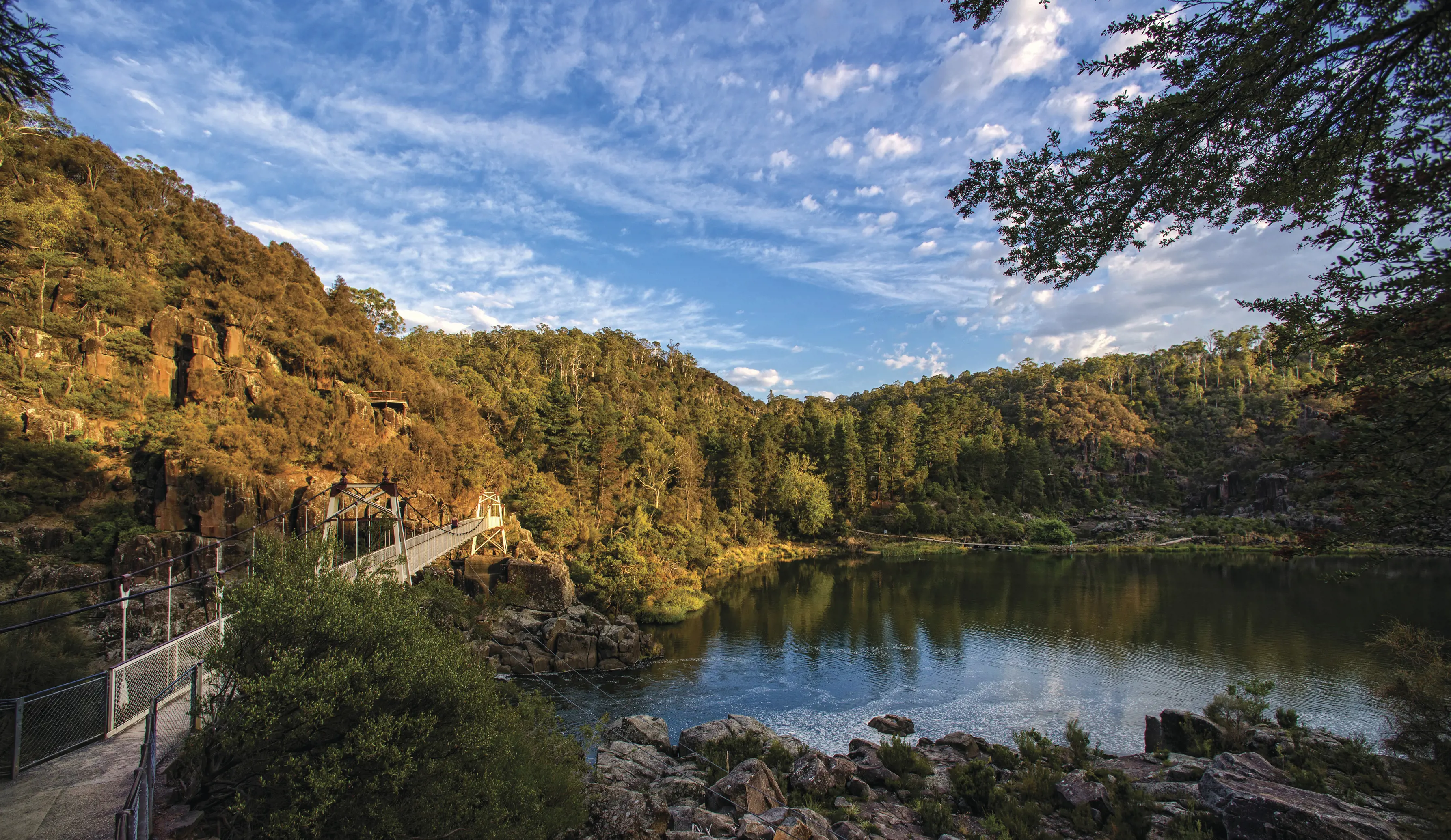 Wide shot of Launceston Cataract Gorge & First Basin with bright blue skies. The Suspension bridge is on the left hand side.