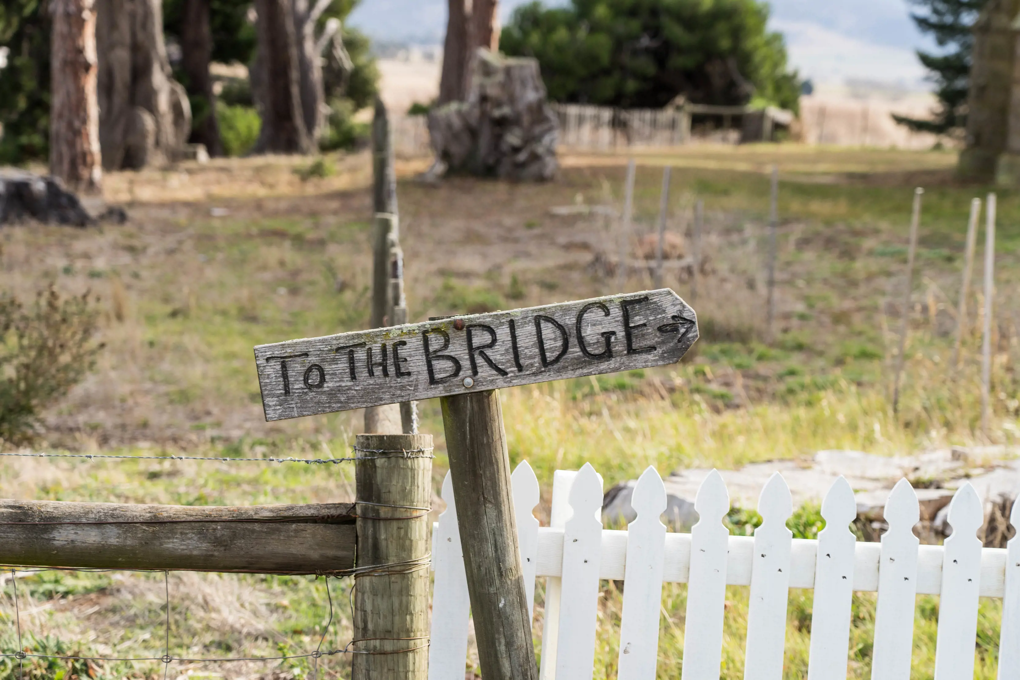 To the Bridge is written on a wooden sign with an arrow pointing towards the brigde at Ross