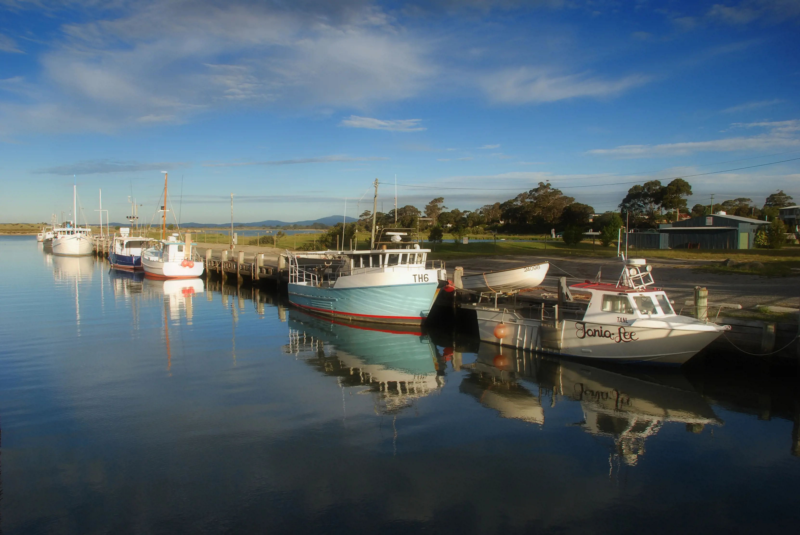 Boats parked up on the still water at Bridport wharf.