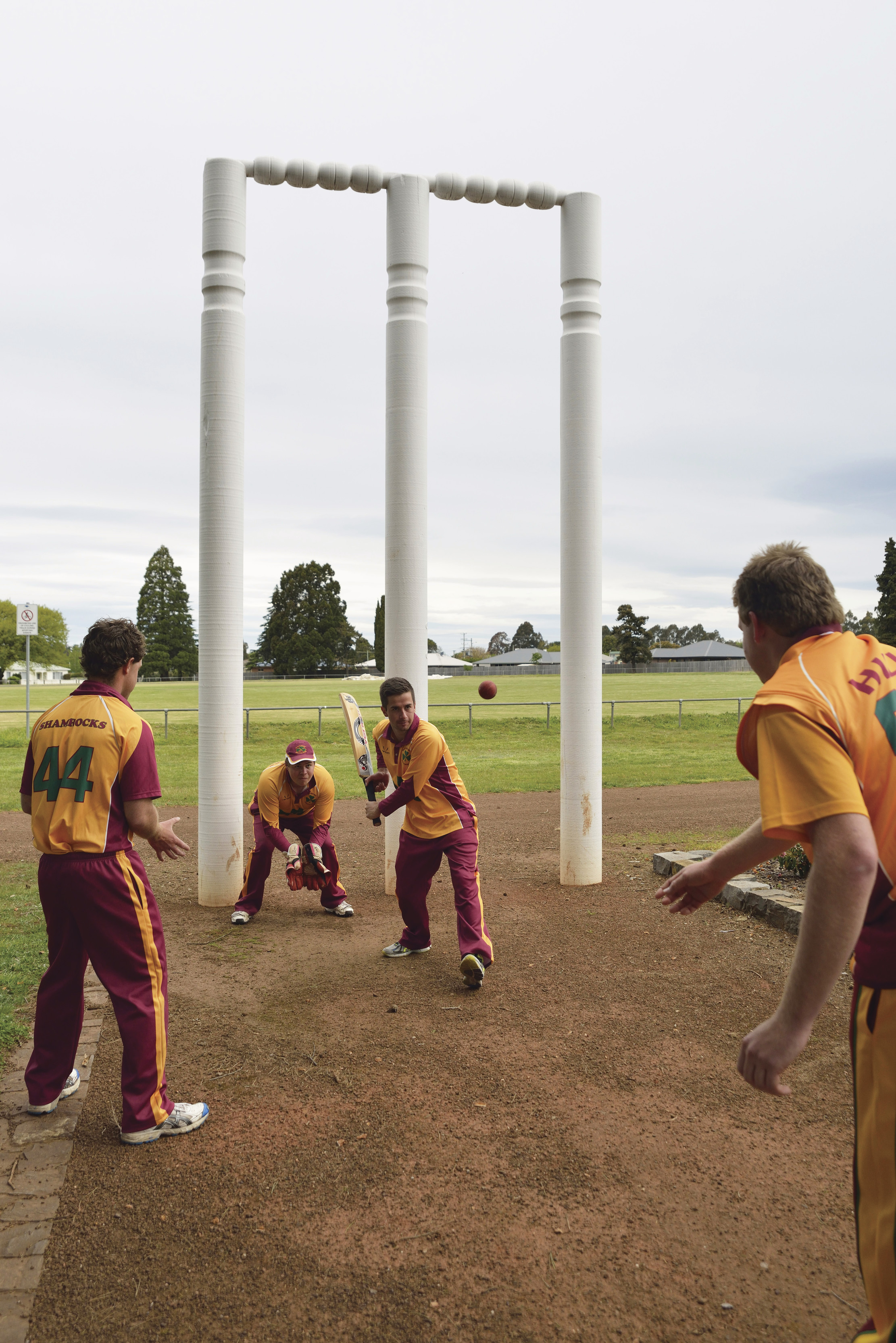A team, playing cricket at The Big Wickets, Westbury. Dressed in the teams red and yellow colours. 