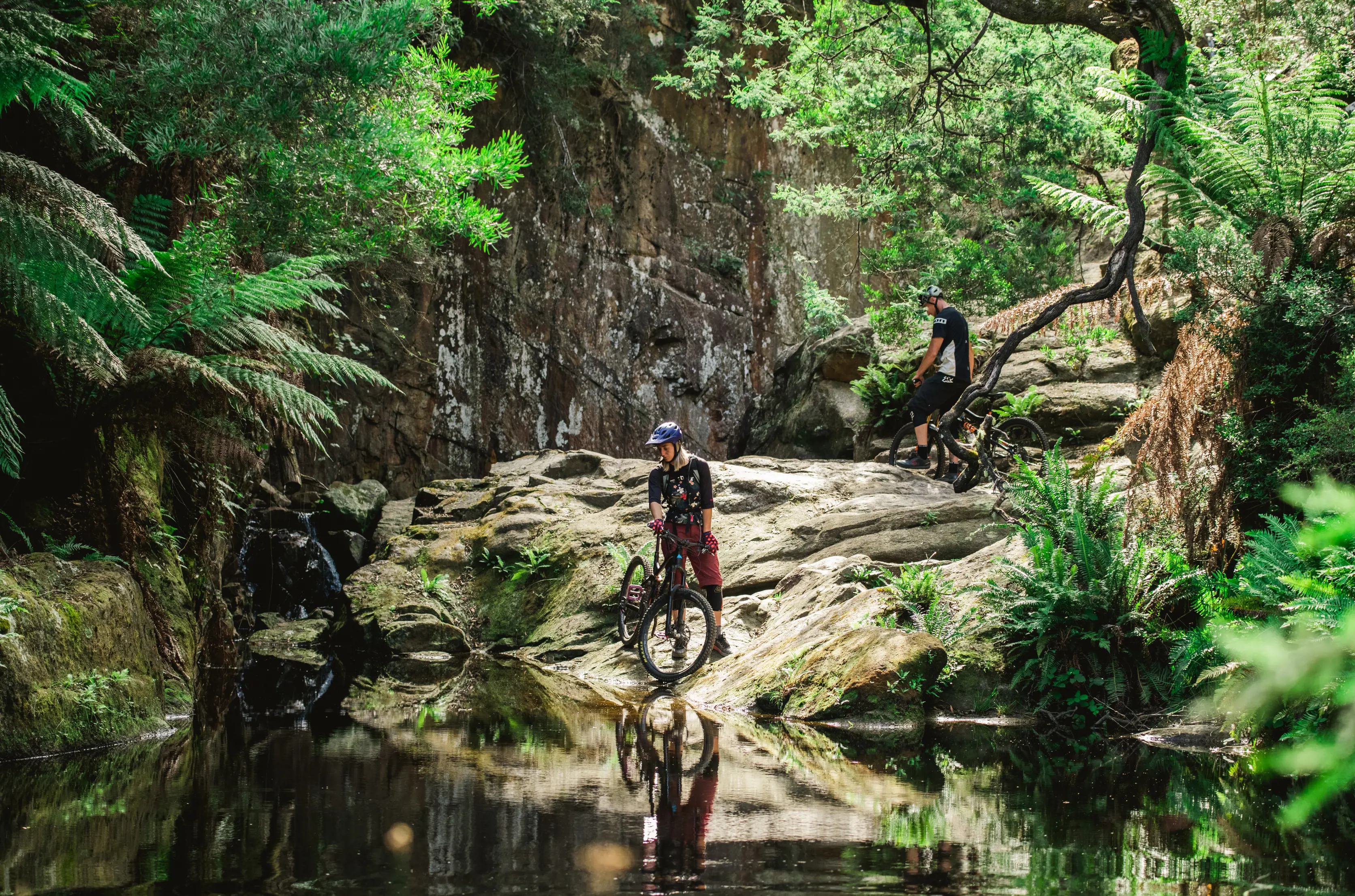 Cyclists stop on the rocks and look over the water at Blue Derby Mountain Bike Trails Derby.