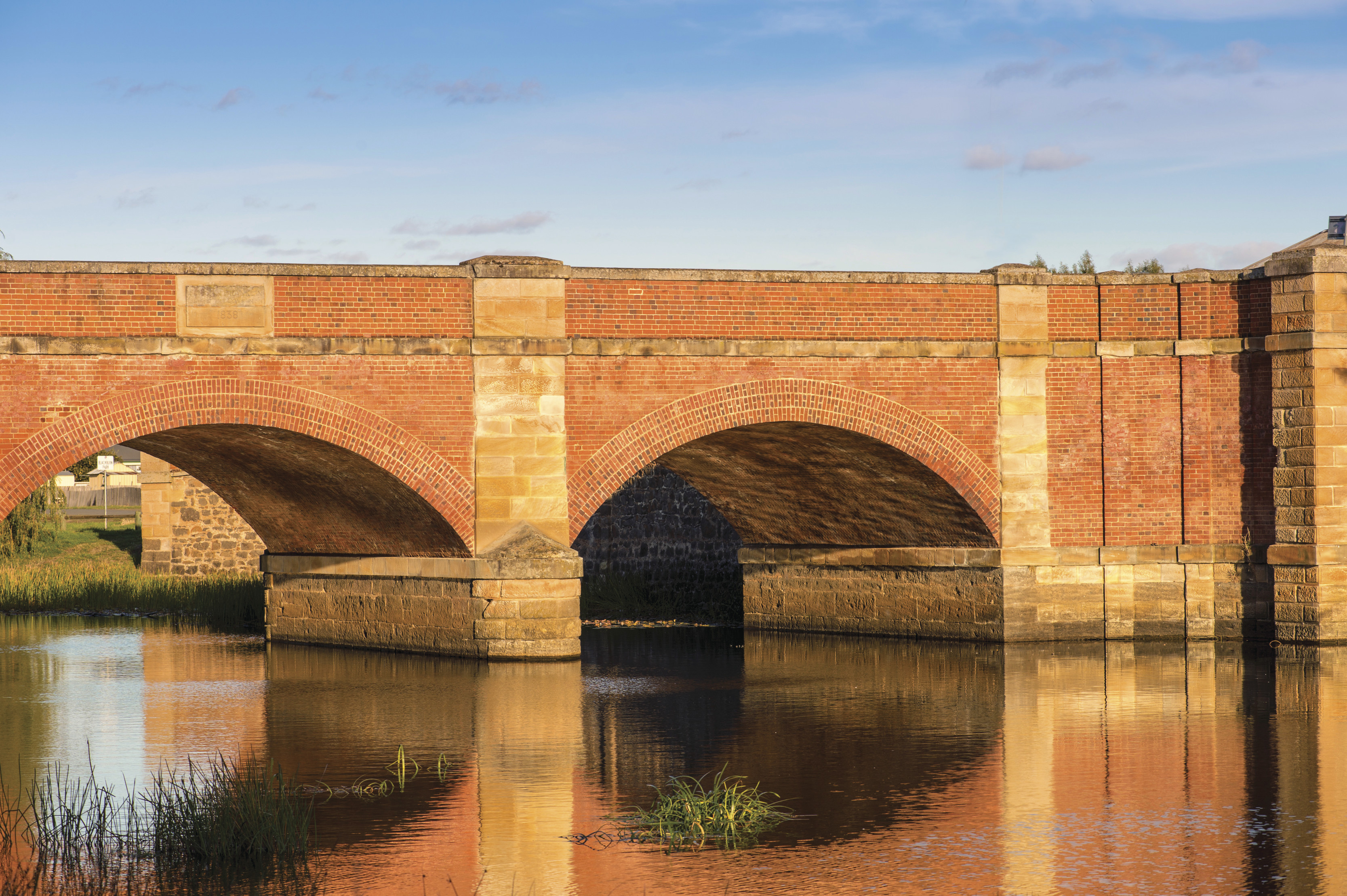 The red brick bridge reflects on the water, in Campbell Town.