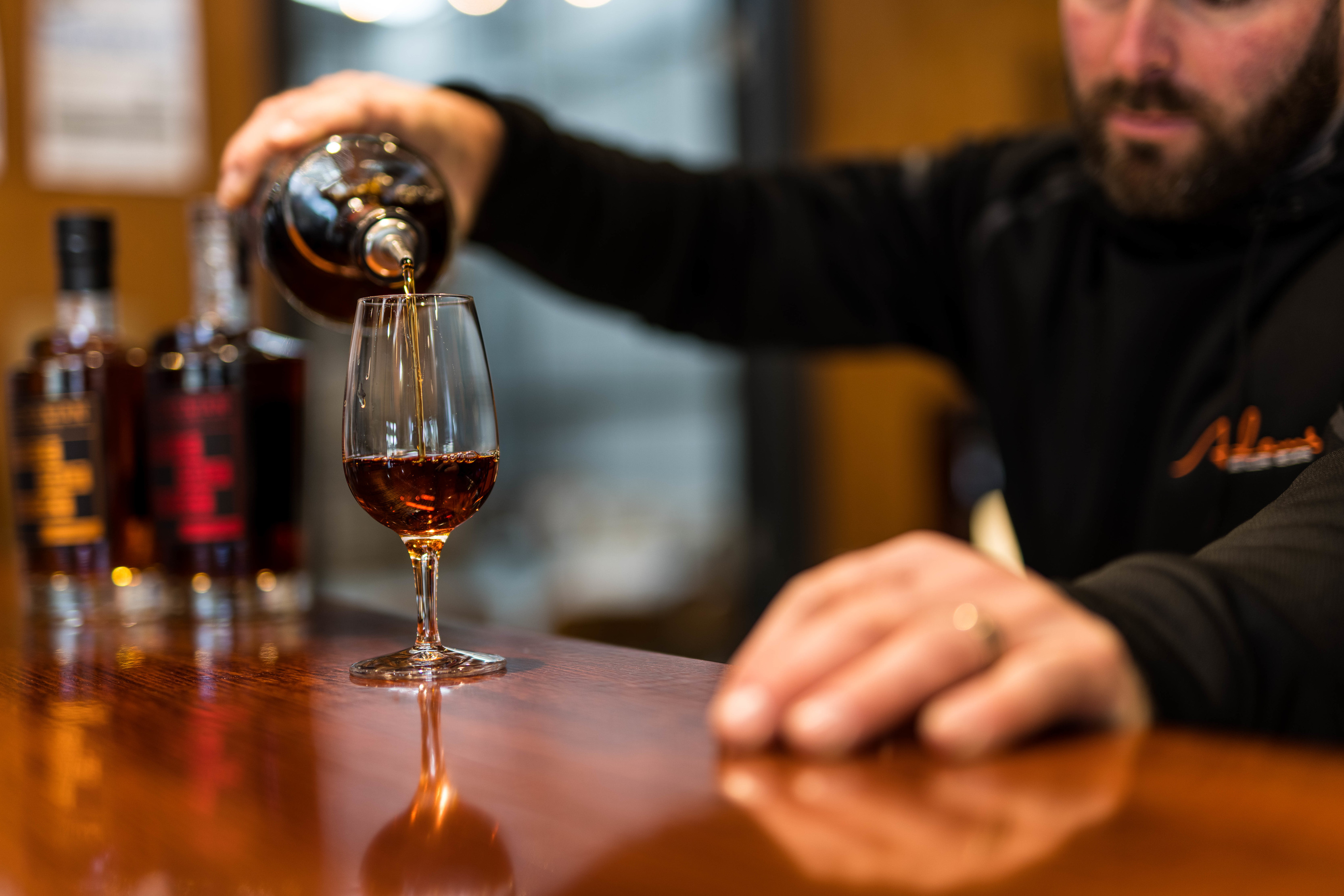Whisky is poured into a glass inside at Adams Distillery.