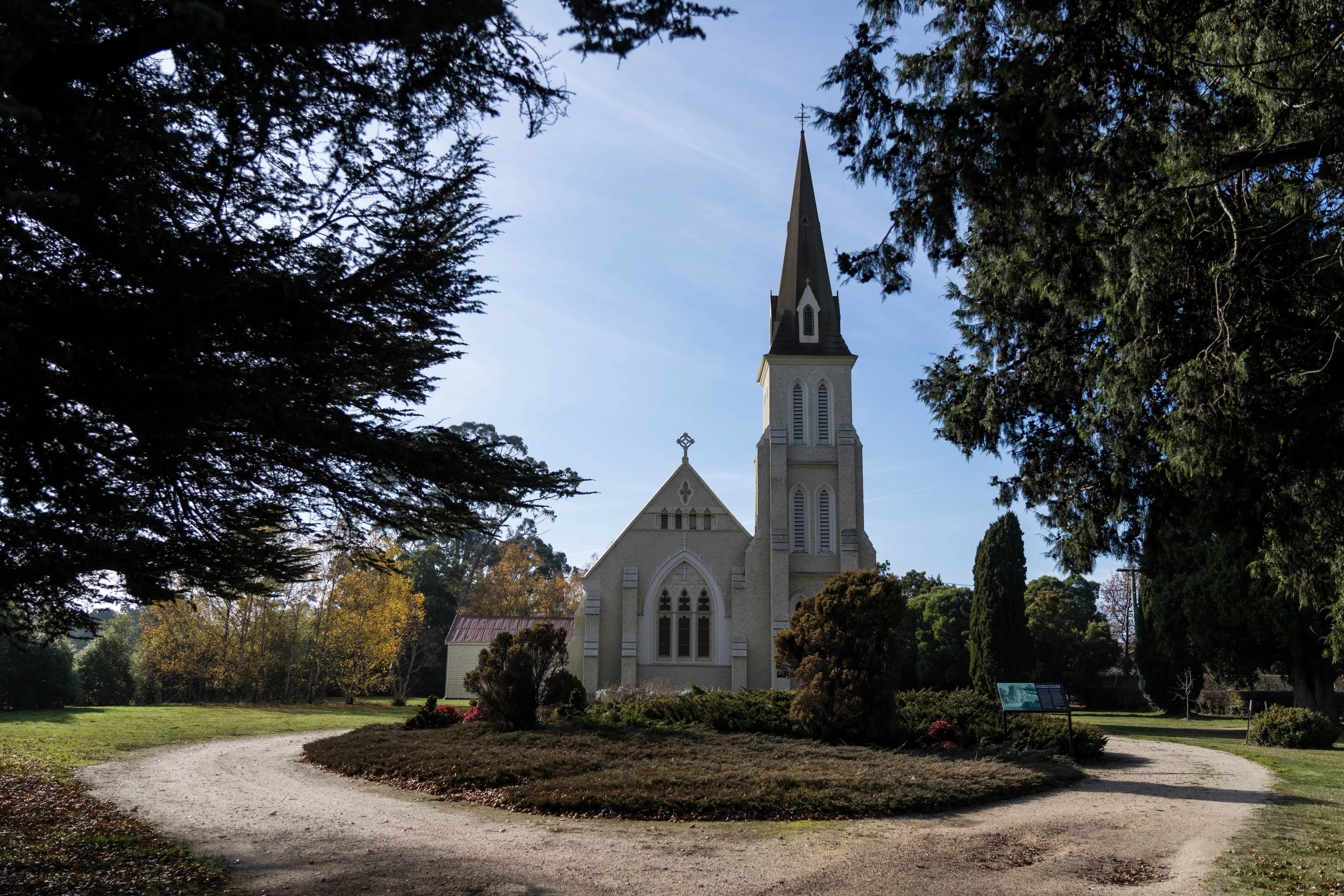 Exterior of the white painted St. Andrew’s Anglican Church, against blue sunny skies.