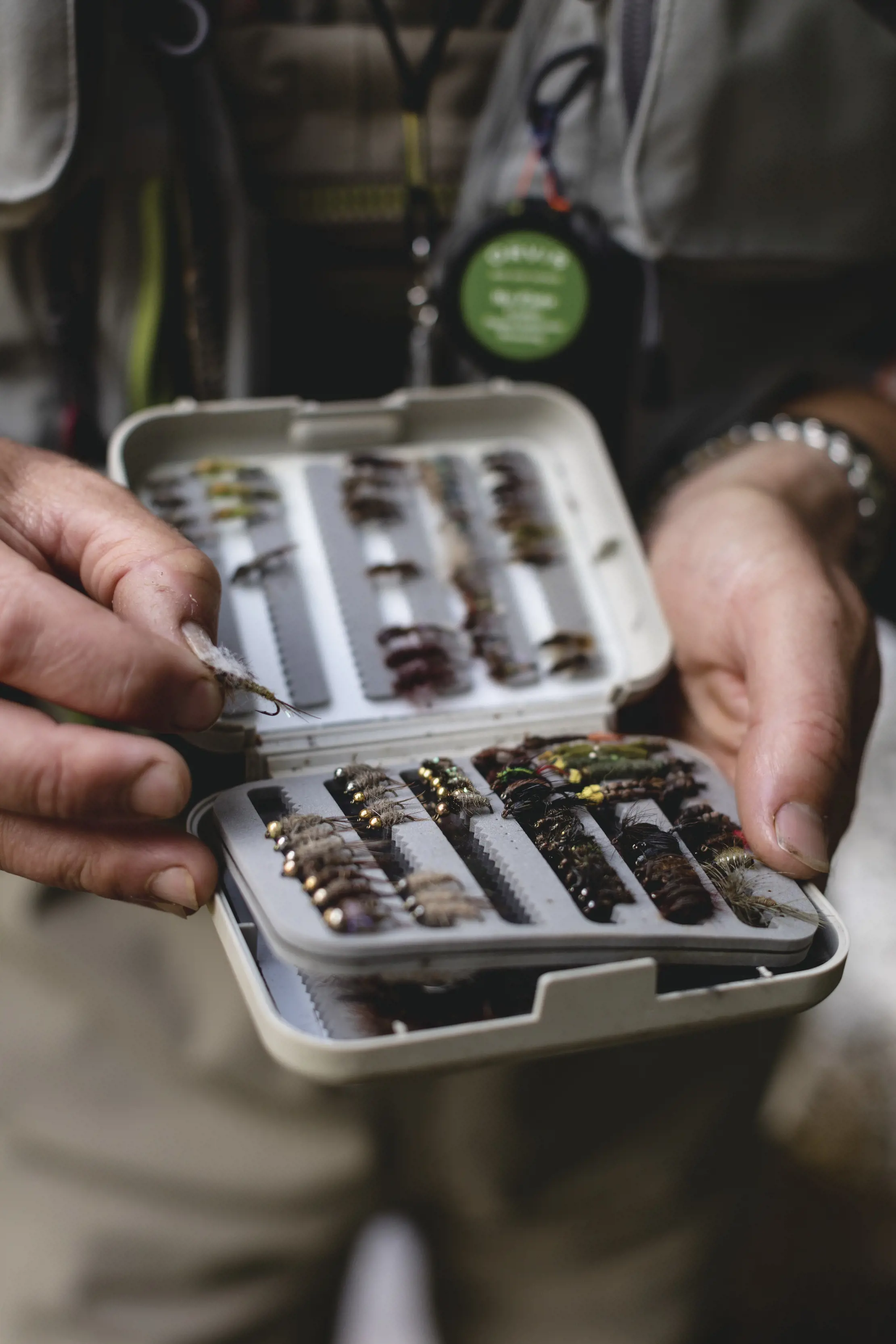 Close up of hands holding a pack of fly fishing lures.