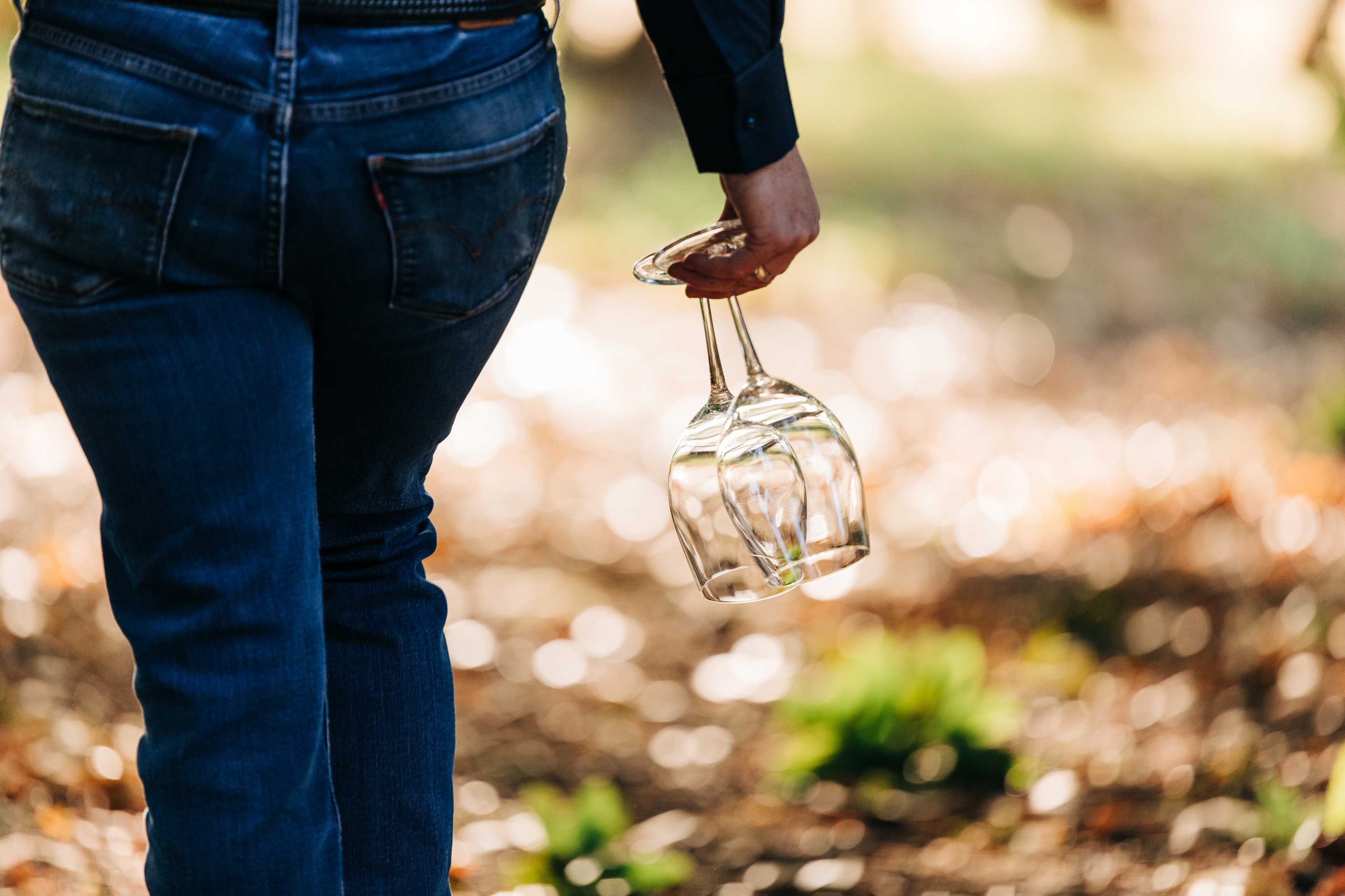 A member of staff carries two empty wine glasses upside down at Holm Oak Vineyards.
