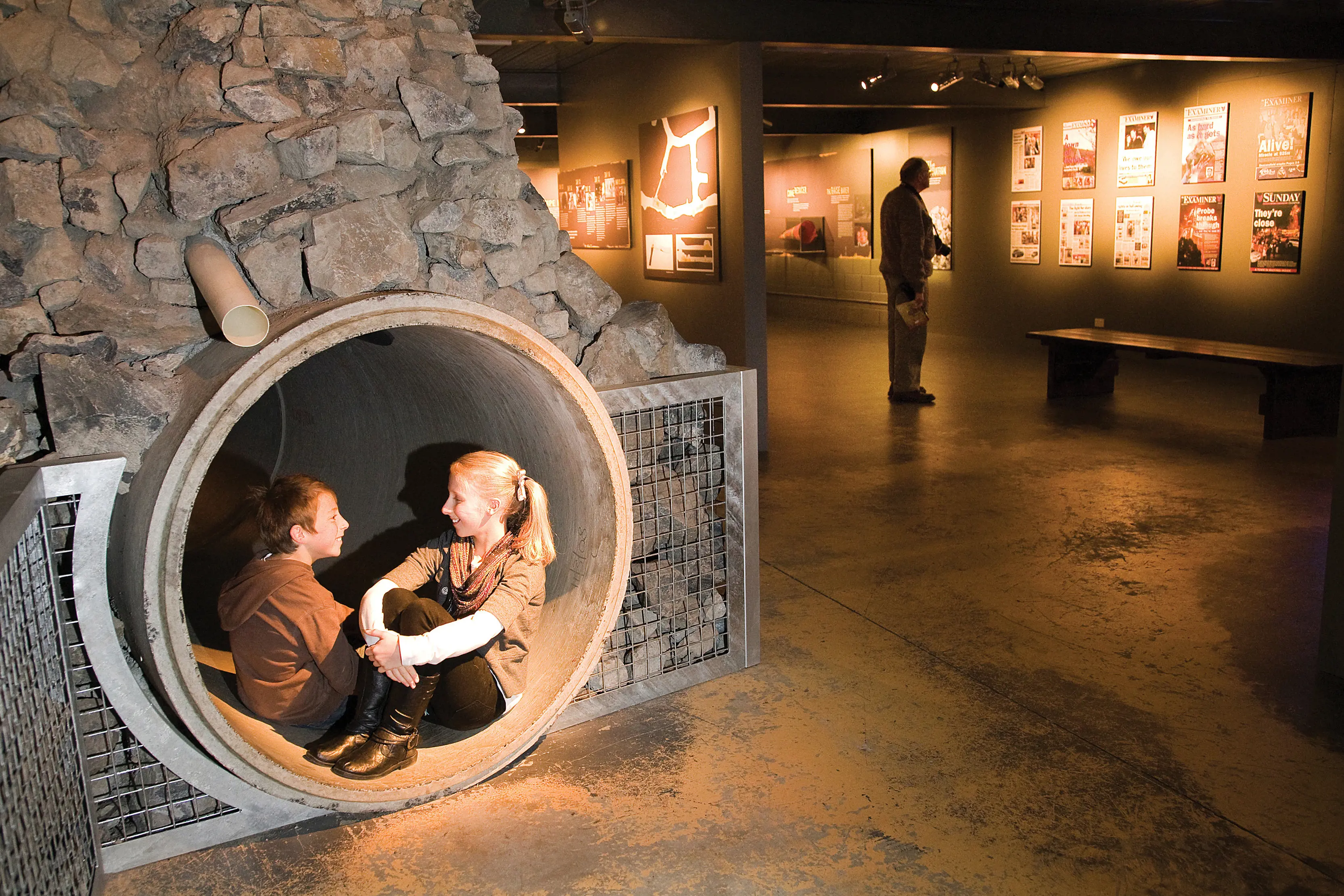 Two children sit in a curved hole in the wall at Beaconsfield Mine & Heritage Centre.