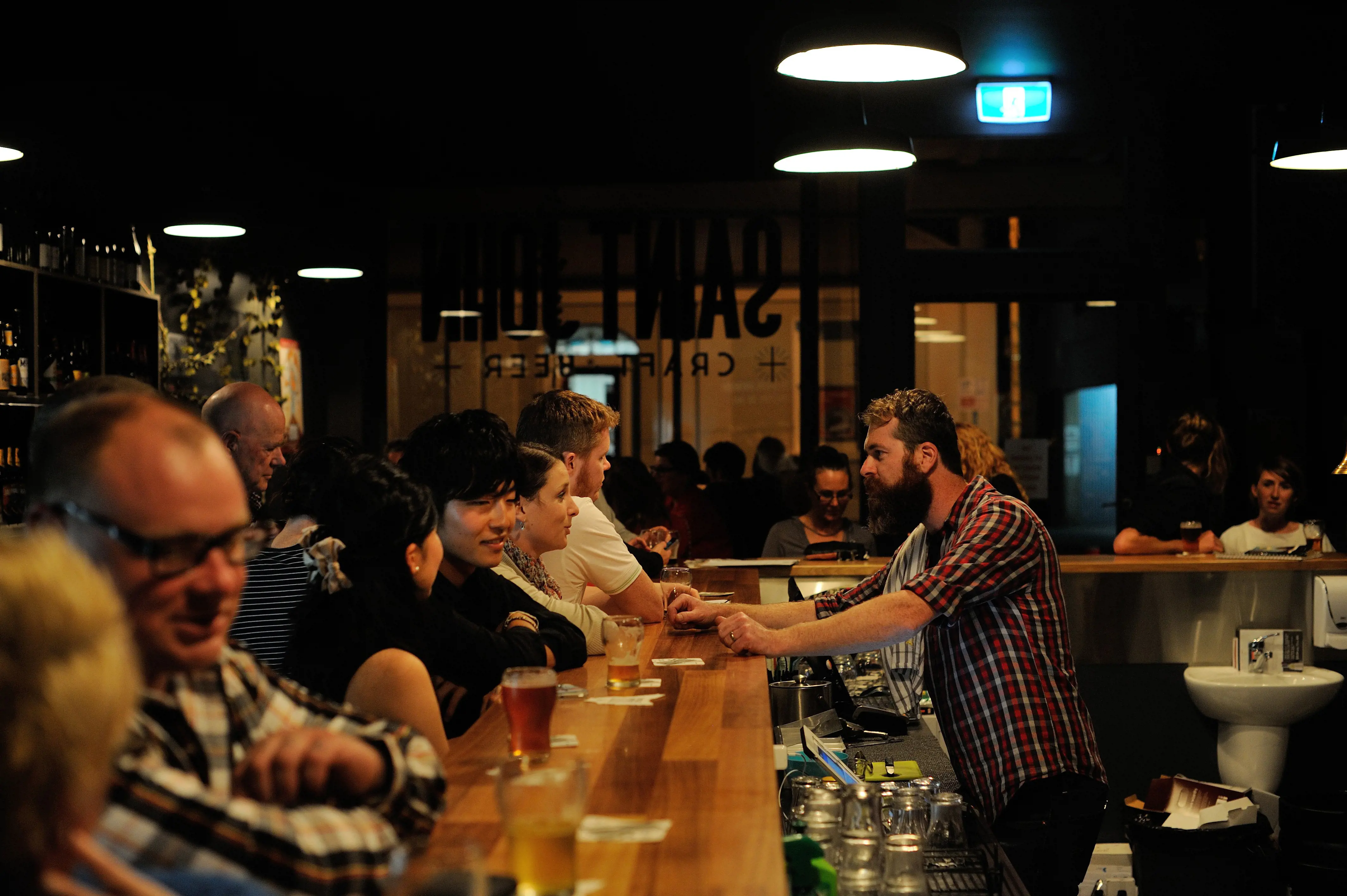 Patrons sitting at a wooden bar with their drinks