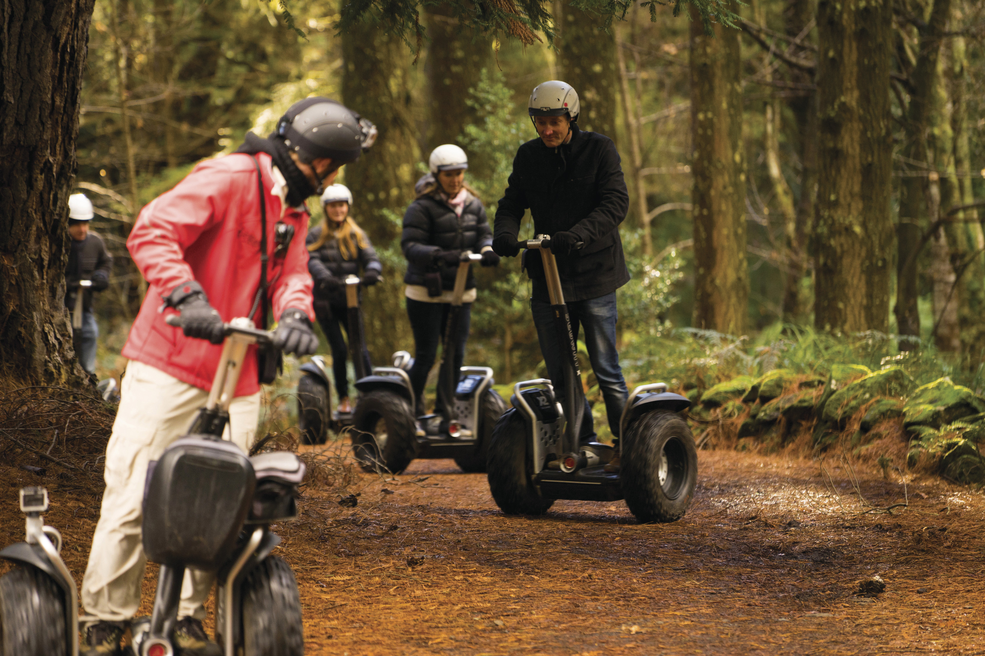 Tour guide for Hollybank Wilderness Adventures and a group of four tourists ride through the forest on off road segways.