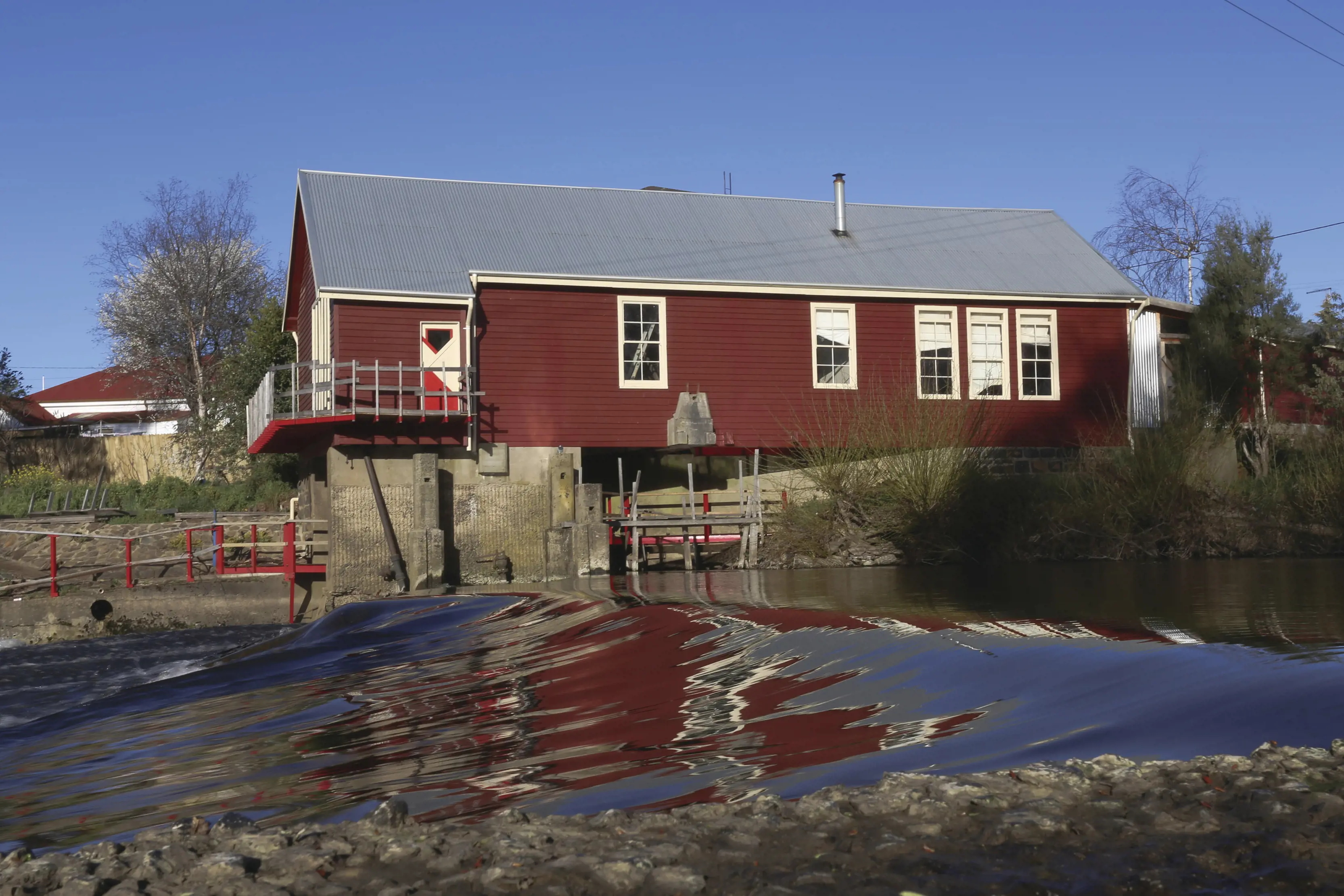 Exterior of the red Deloraine cottage building, next to the Meander River.