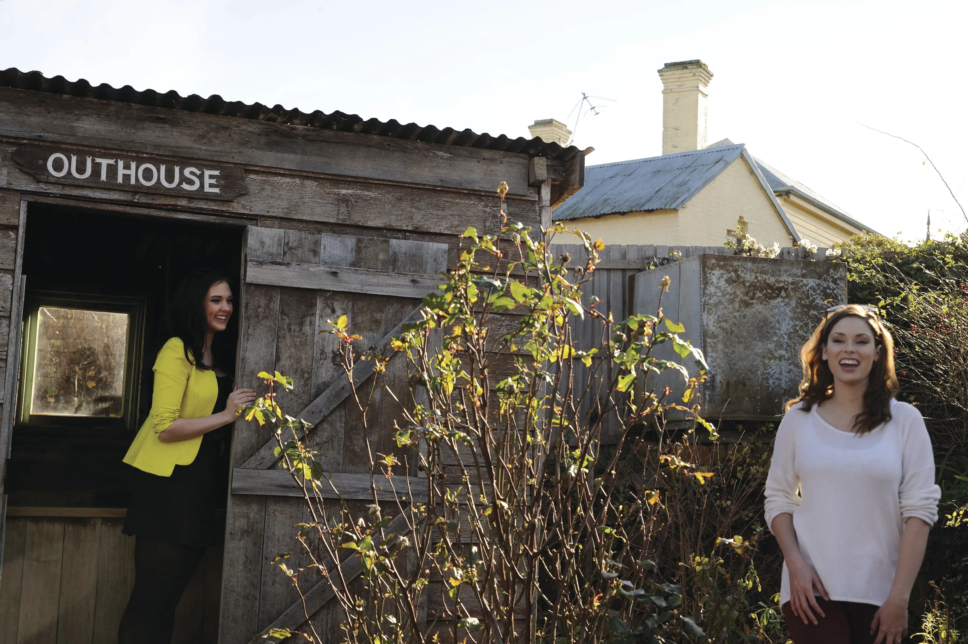 Two friends having fun by the outhouse at Deloraine Folk Museum.