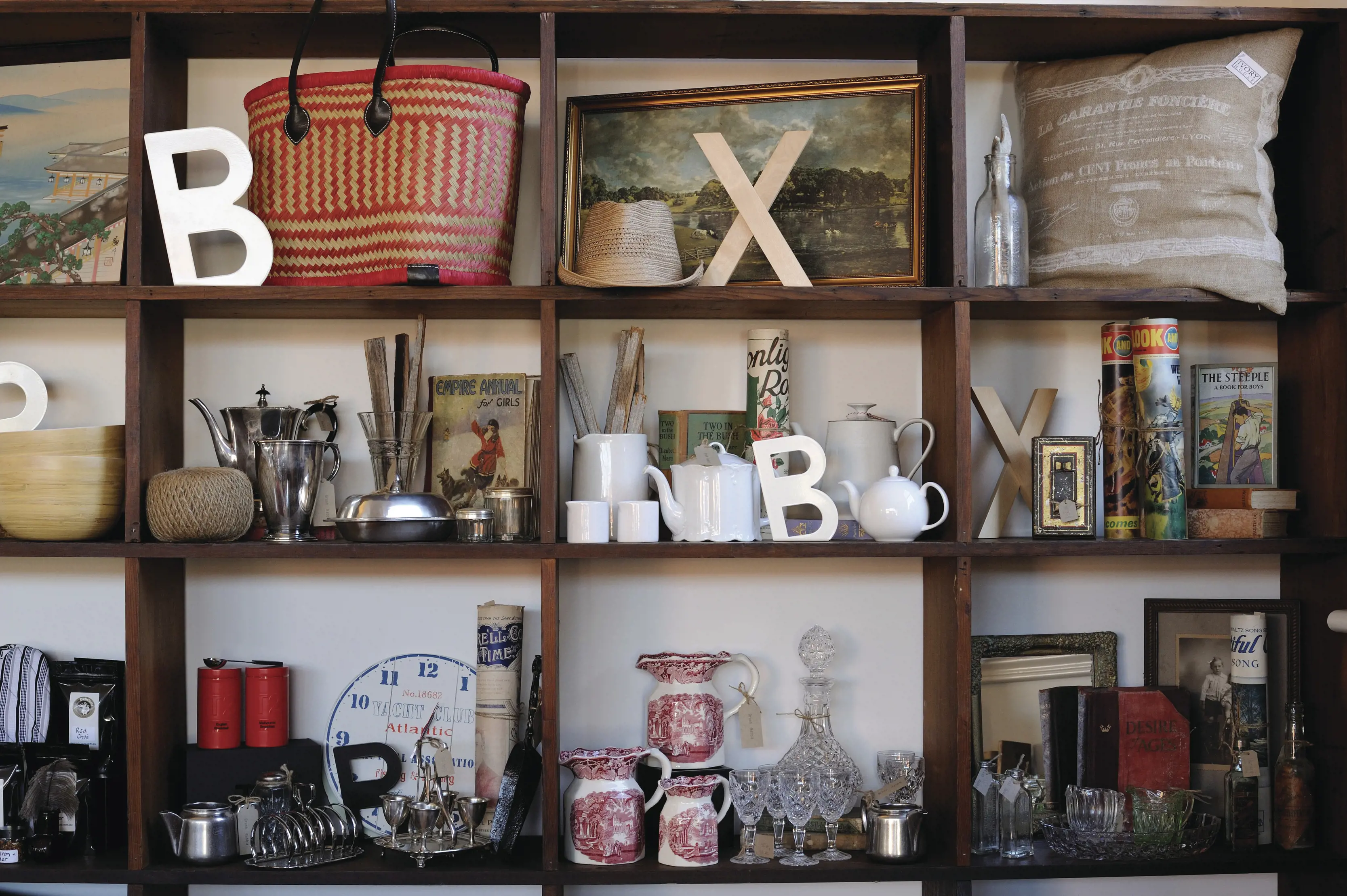 Close up of a set of shelves packed with products, including letters, bags, glasses, clock, cushion and more, in a shop in Deloraine.