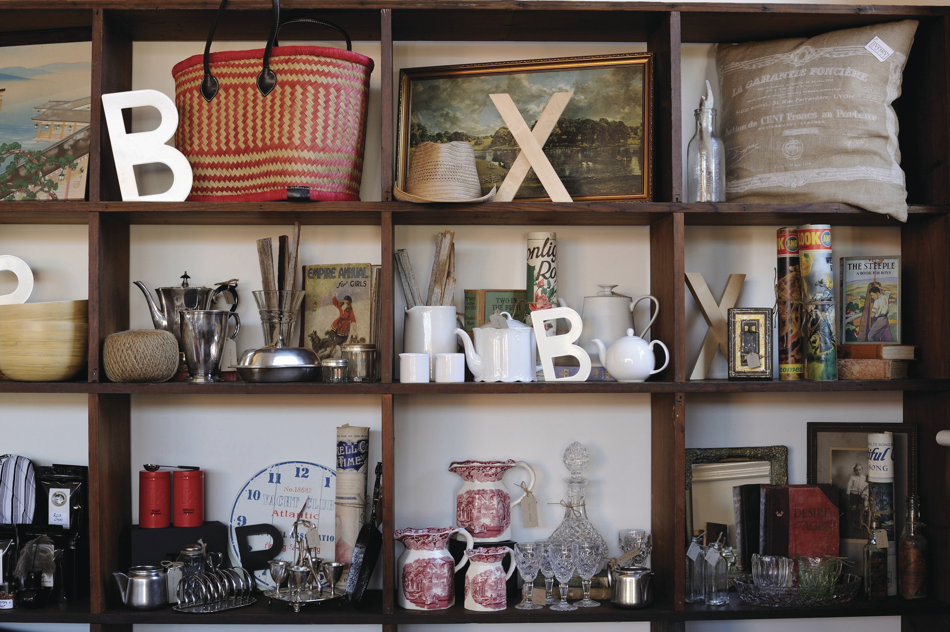 Close up of a set of shelves packed with products, including letters, bags, glasses, clock, cushion and more, in a shop in Deloraine.