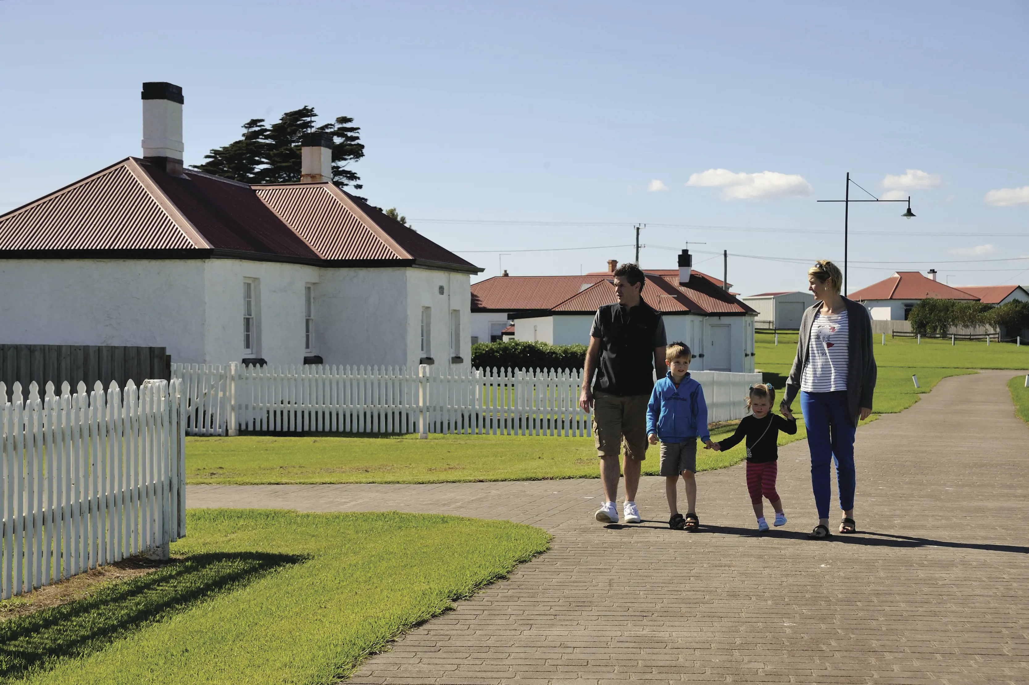 A family holding hands walk through the grounds at Low Head Pilot Station.
