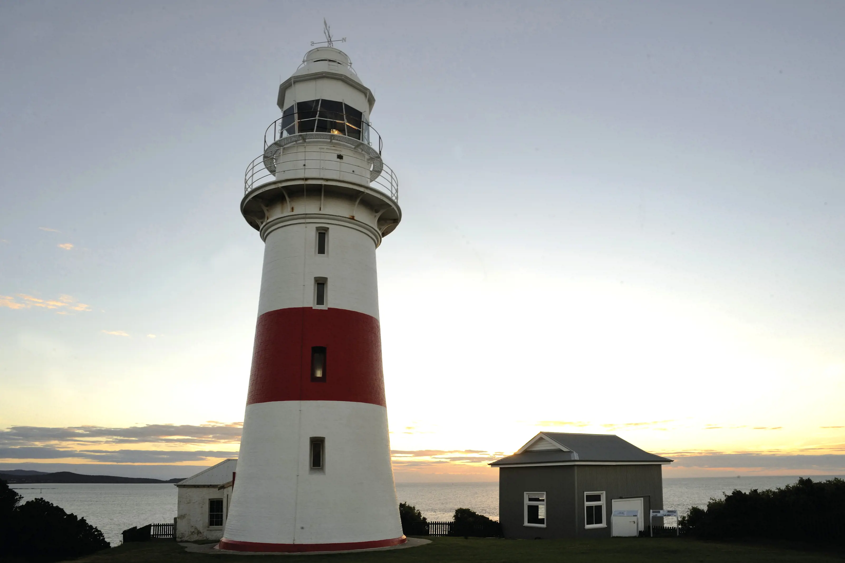 Close shot of Low Head Lighthouse, with a collection of cottages surrounding and beautiful water views.