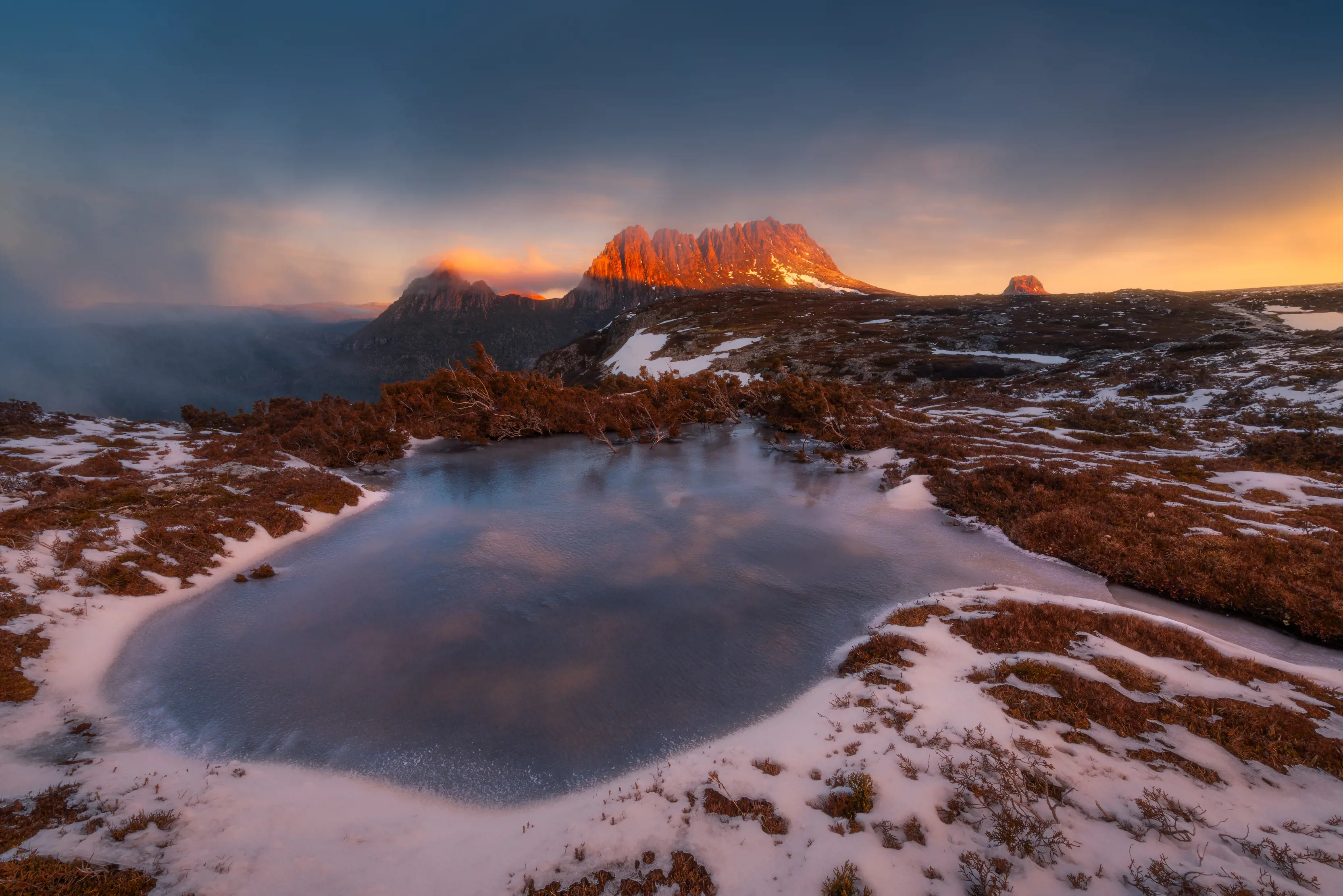 Spectacular aerial image of Cradle Mountain during sunrise. Vibrant, warm tones fill the scene. 