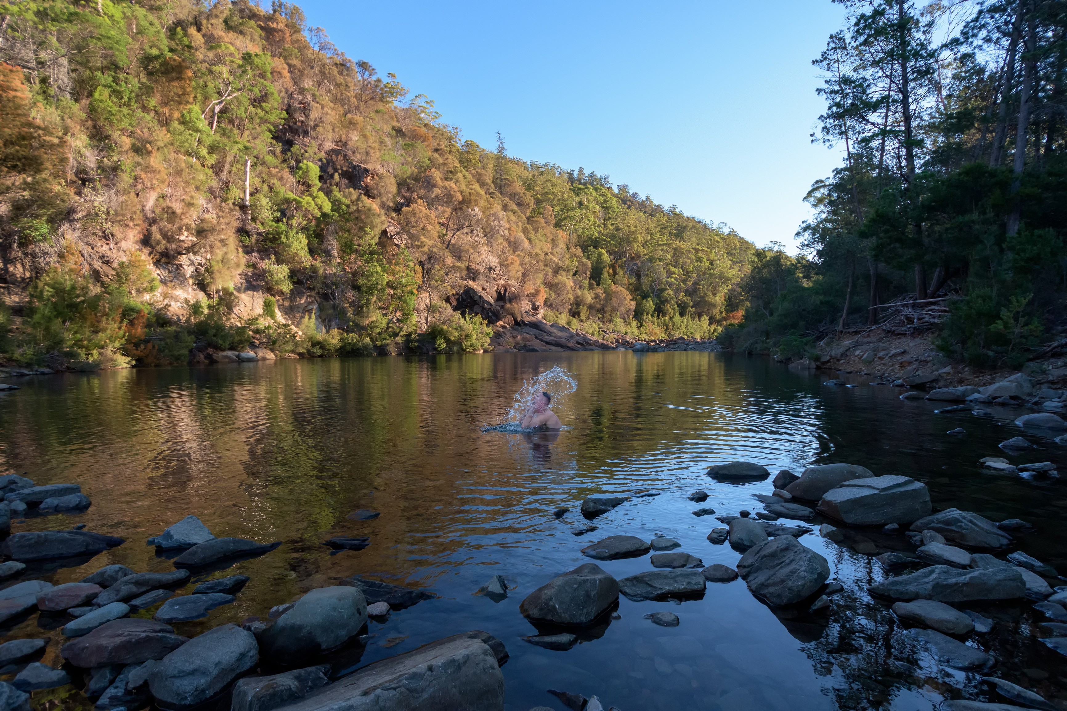 Person swimming at Apsley Gorge, surrounded by rugged rocks and forest.