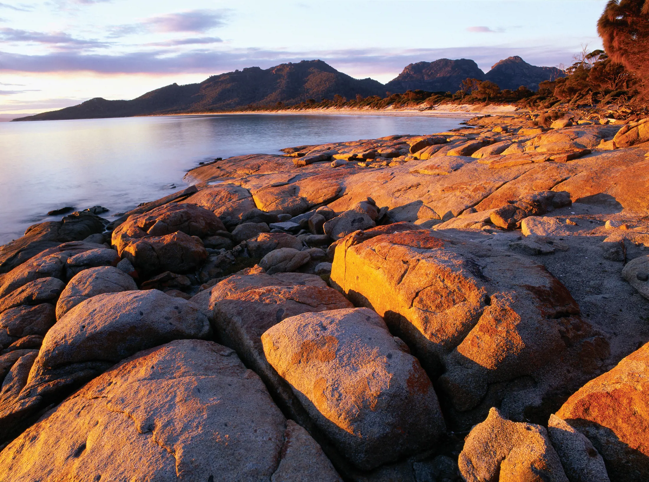 Breathtaking image of Hazards Beach, with glorious white sand, forests and great chunks of granite, extraordinary warm colours appear as the sun sets.