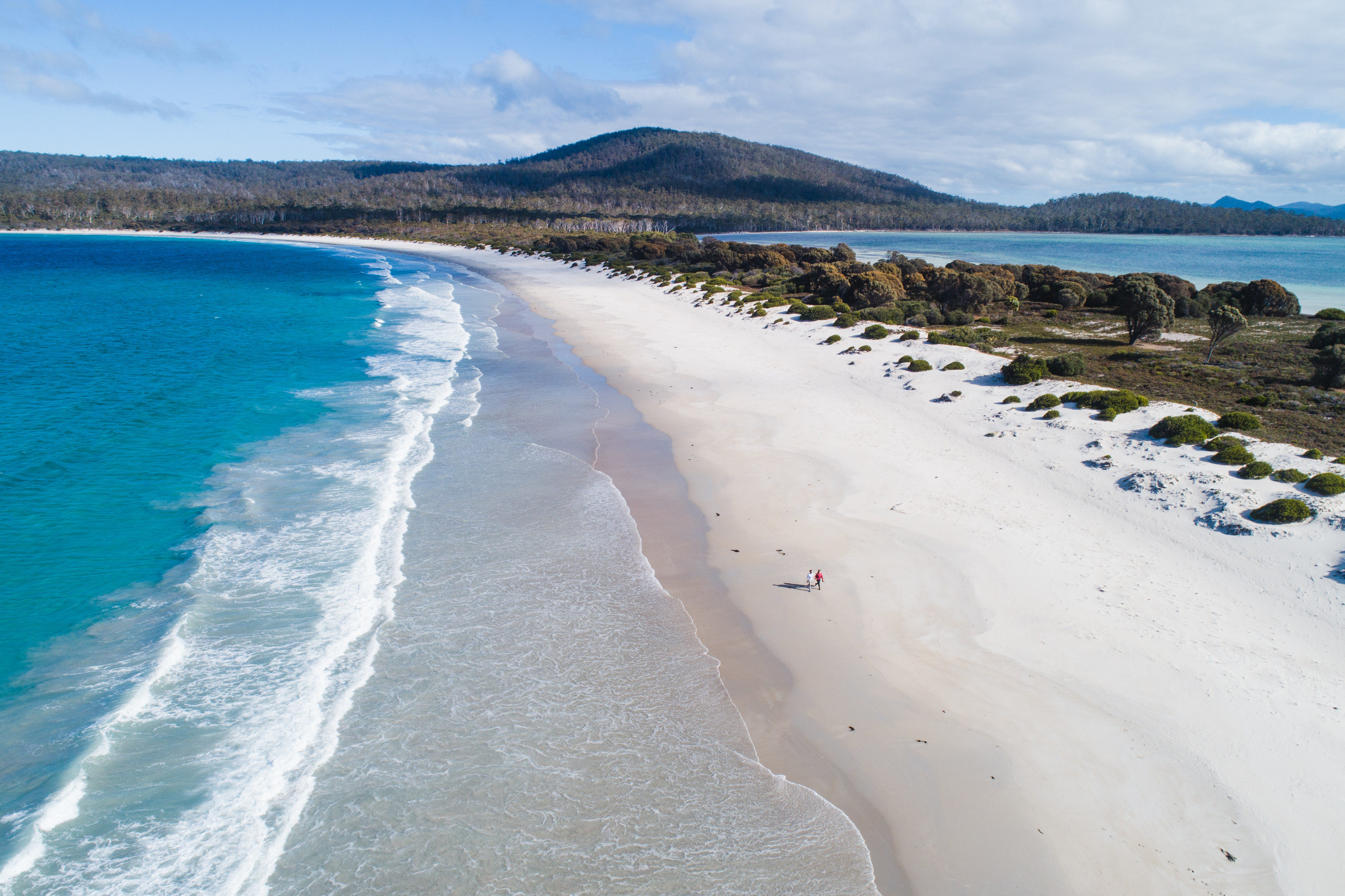 Incredible aerial image of a couple walking along Ocean Beach, Maria Island, on a clear, sunny day.