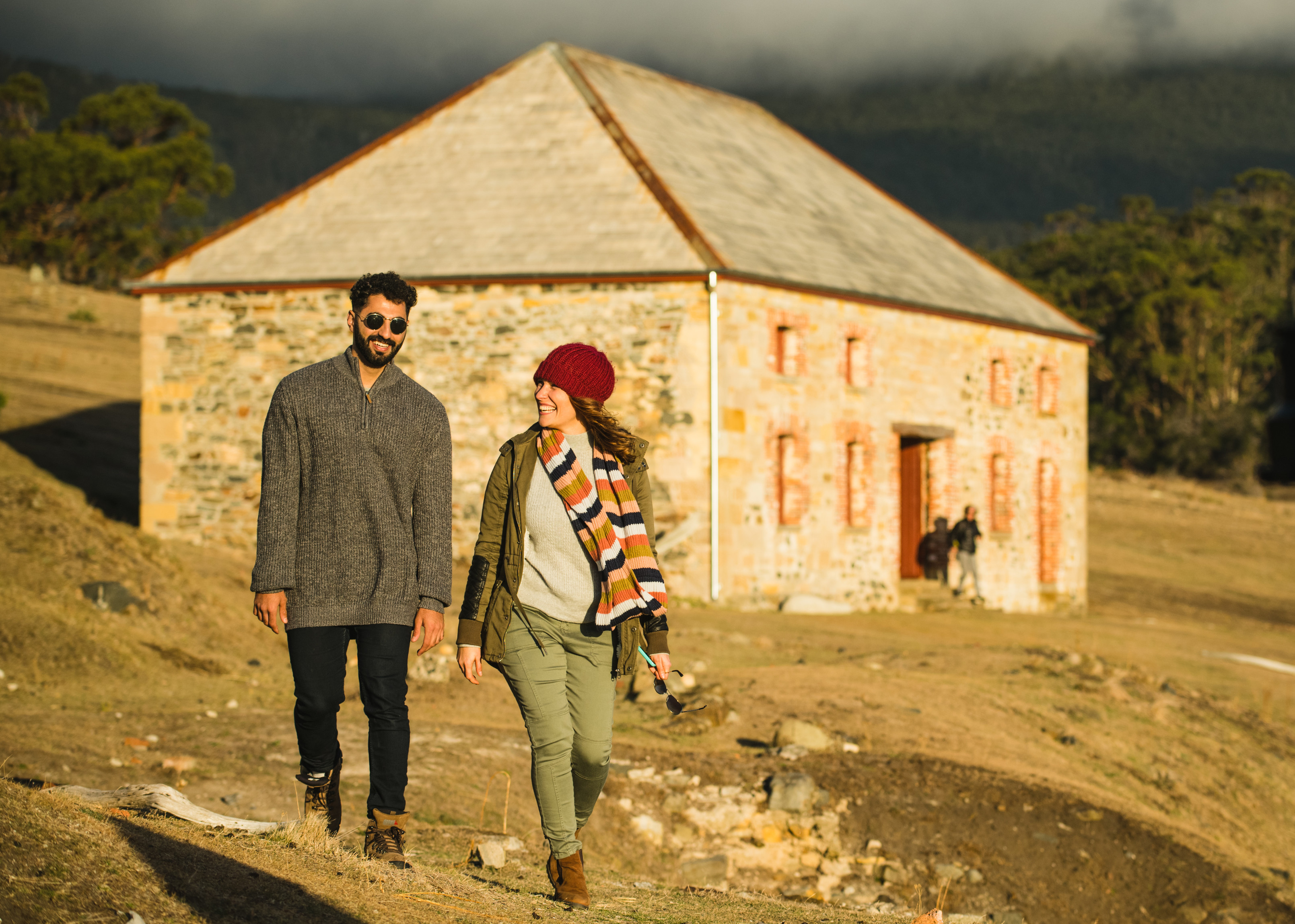 Couple smiling, walking away from the Commissariat Store, Maria Island, towards the camera.
