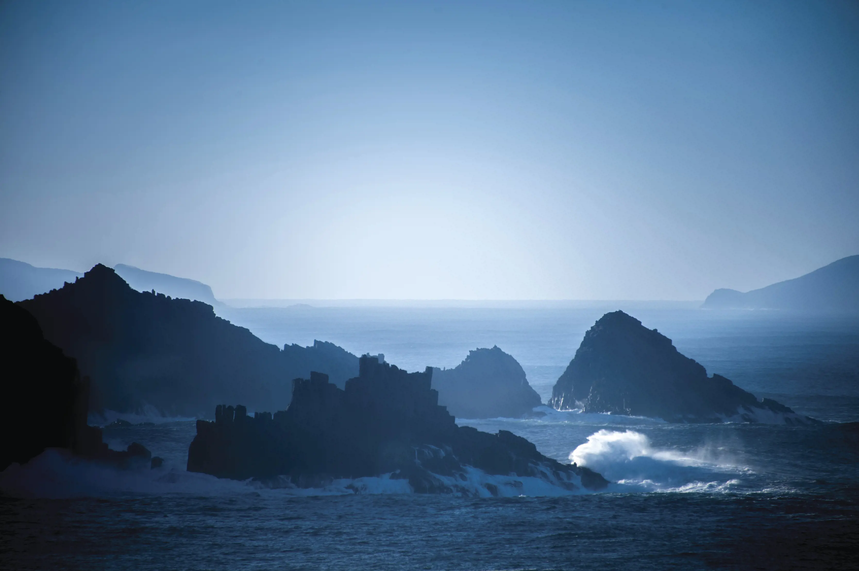 Dramatic and moody image of Cape Bruny as waves crash against the cliffs.