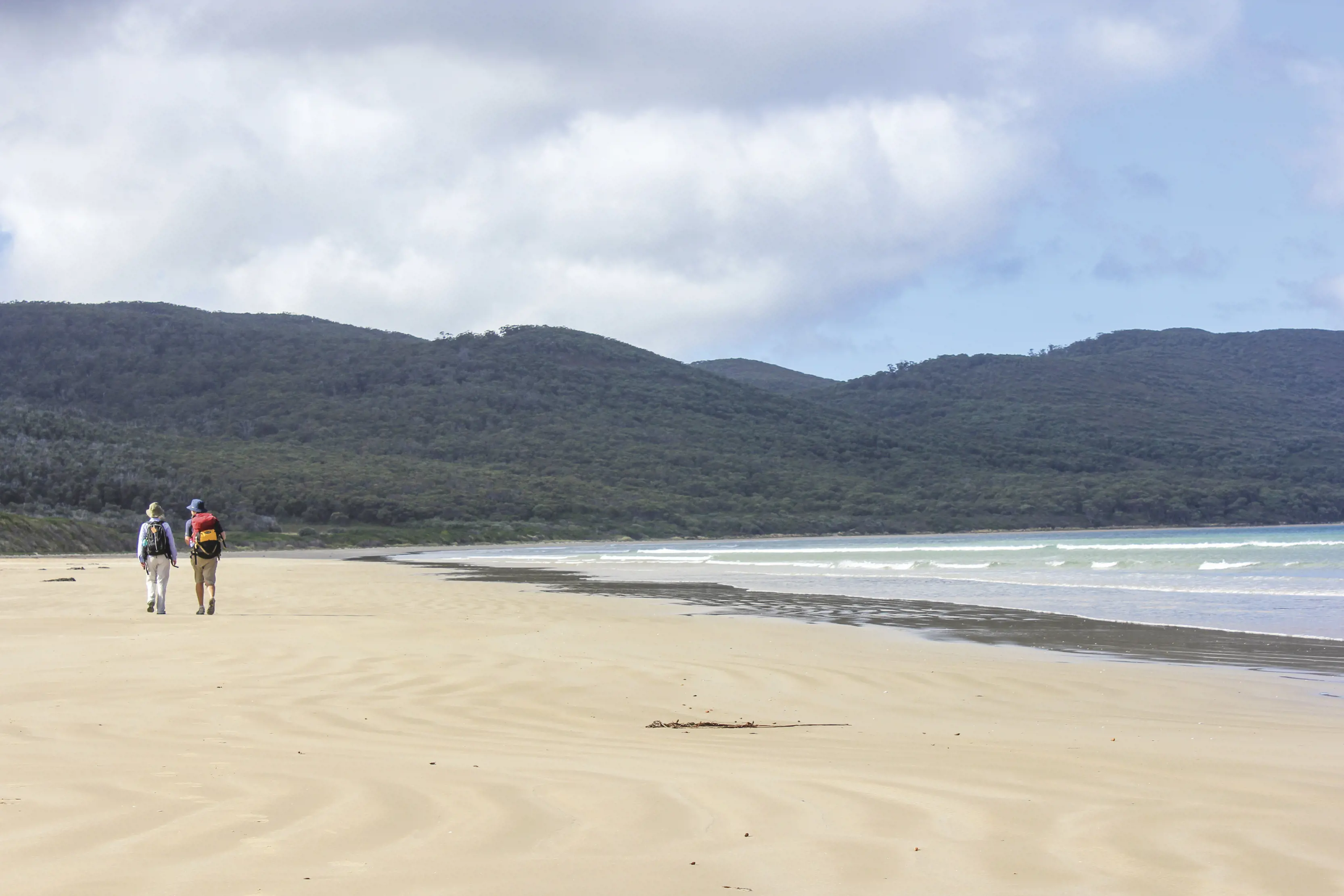 Couple walking along the beach on a beautiful sunny day in Cloudy Bay, Bruny Island.