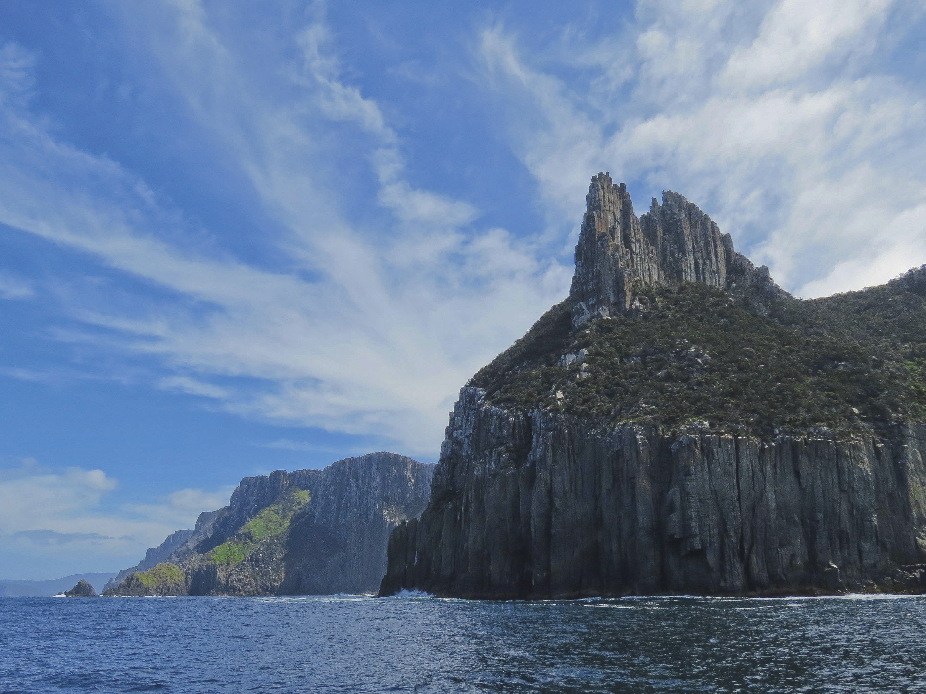 Incredible view of Cape Pillar and The Blade from the ocean with Tasman Island Cruise. Large cliff faces surrounded by deep blue ocean. 