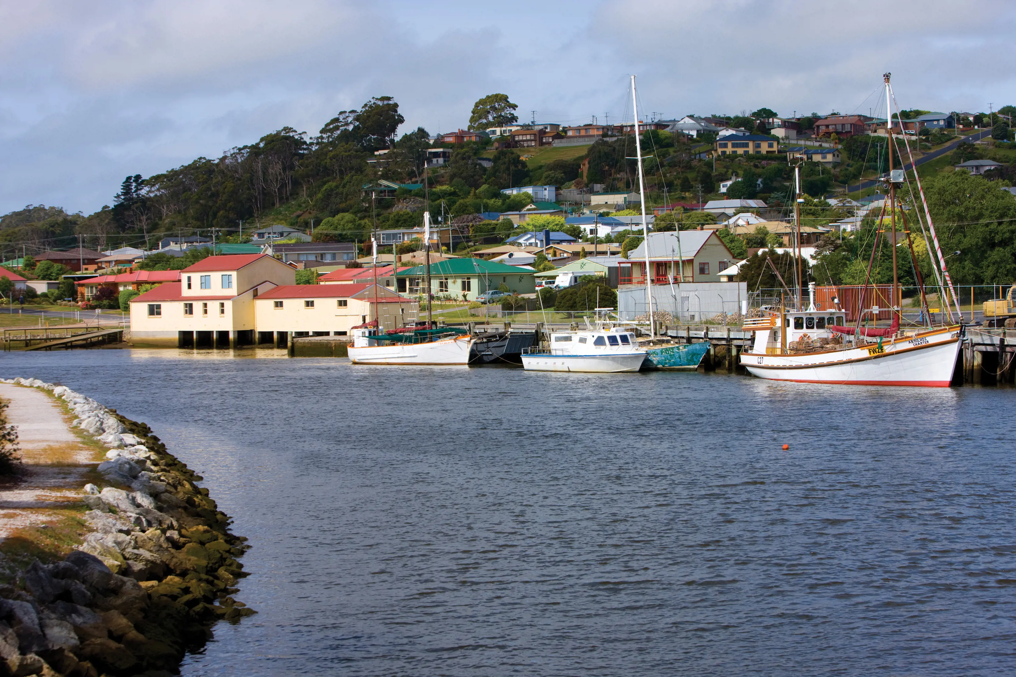 Duck River, Smithton, with boats docked at the jetty and buildings fill the background of the image with the river taking up the foreground.