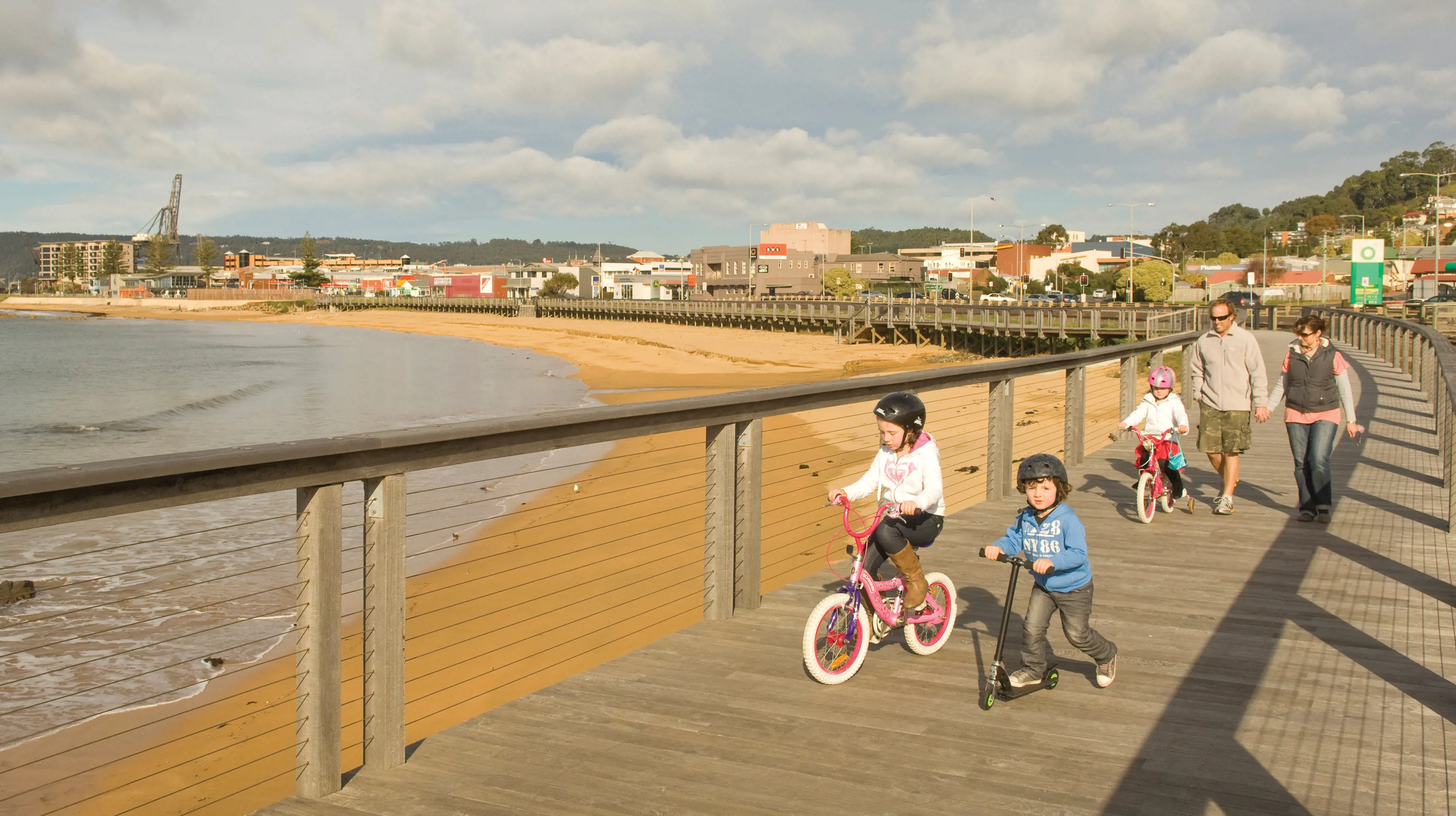 A family taking a bike ride along Burnie beach.