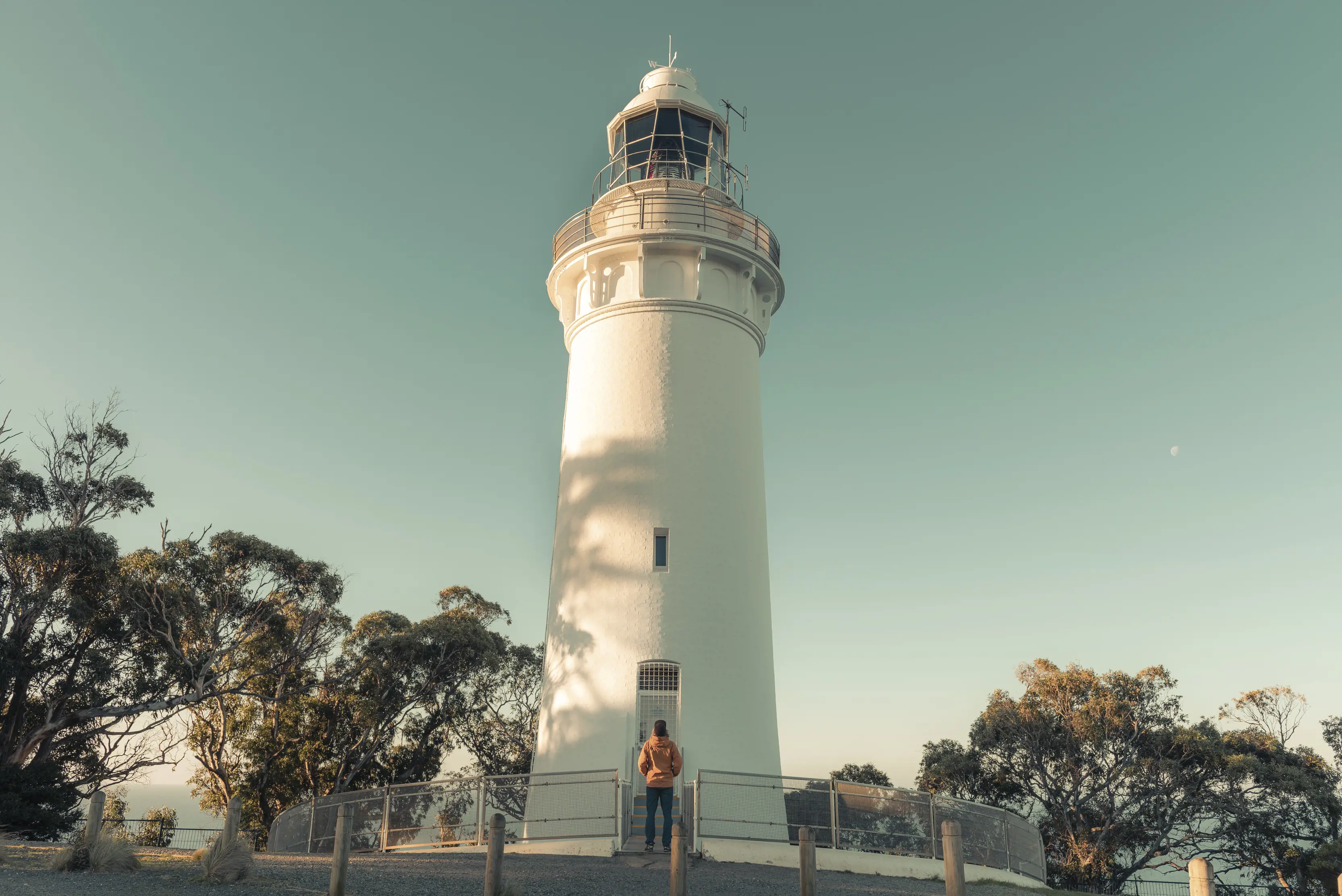 Image of the Table Cape Lighthouse with a person looking up at it from the front door.