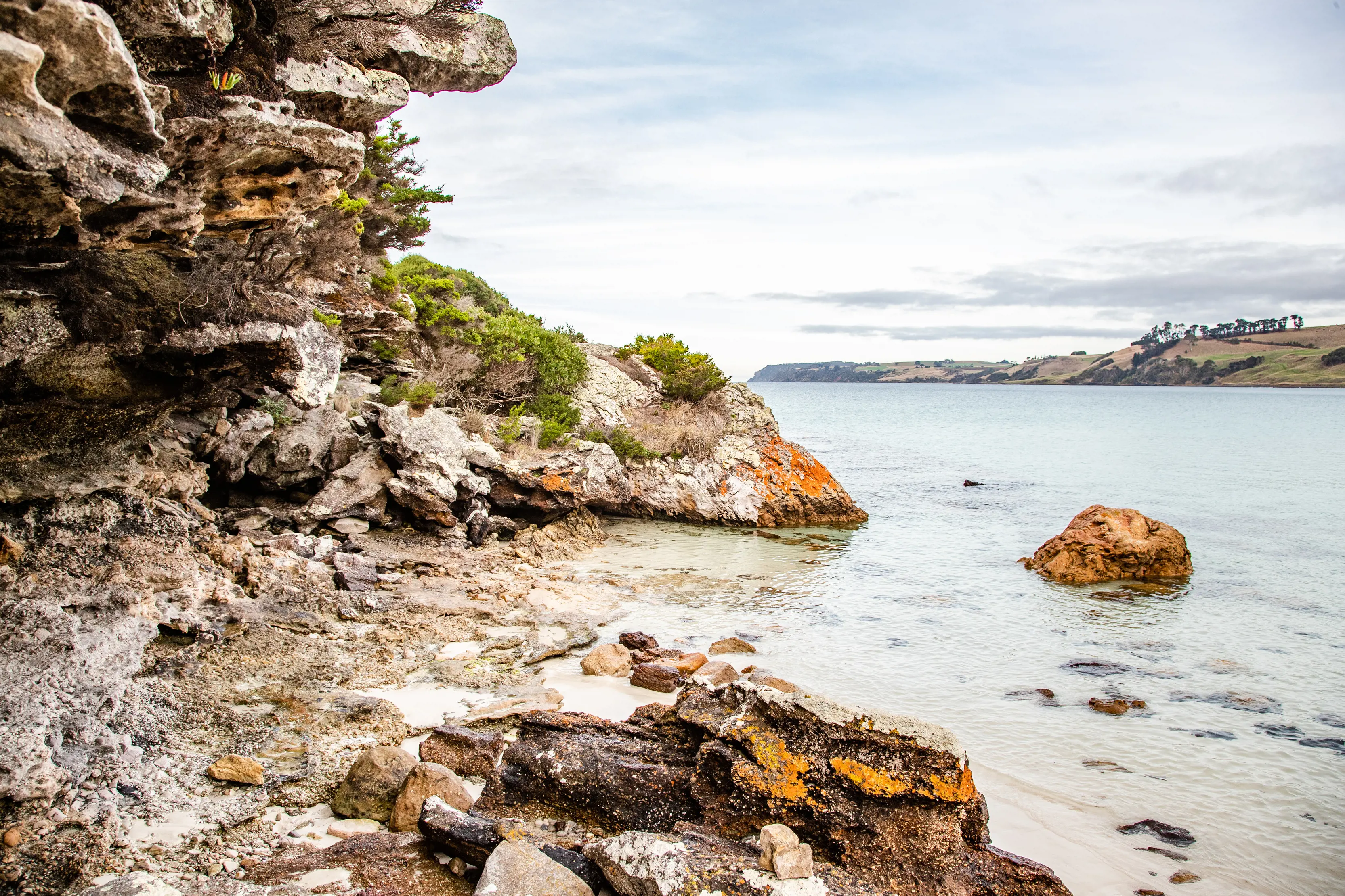 A shallow rock cave fills the left side of the image that runs to the clear water of Boat Harbour.