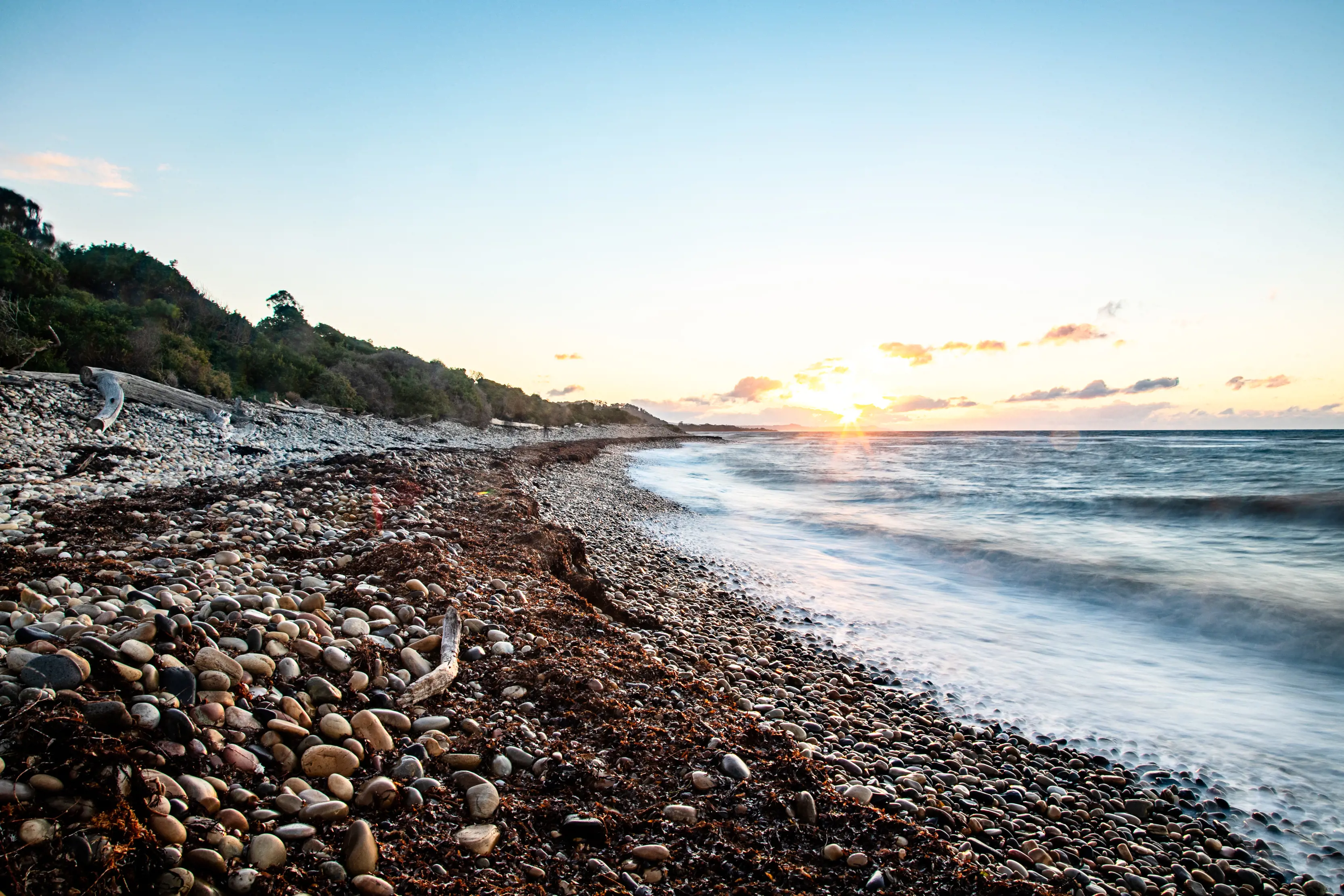 A wide angle Image of the pebbly shore of Lillico Beach, during a spectacular sunrise.