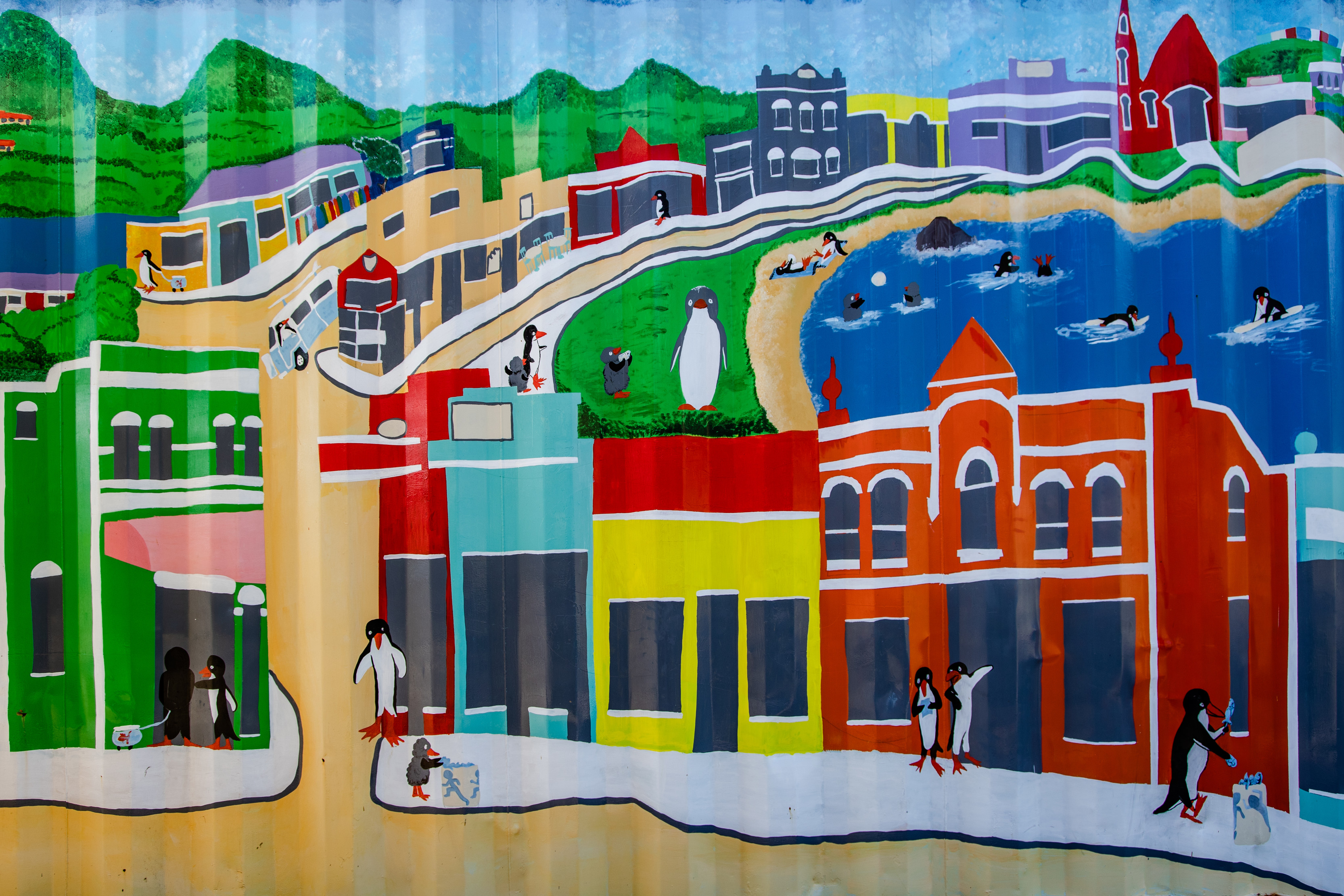 A cute mural of the Penguin foreshore, depicting the people as penguins. Filled with vibrant colours and a playful vibe.