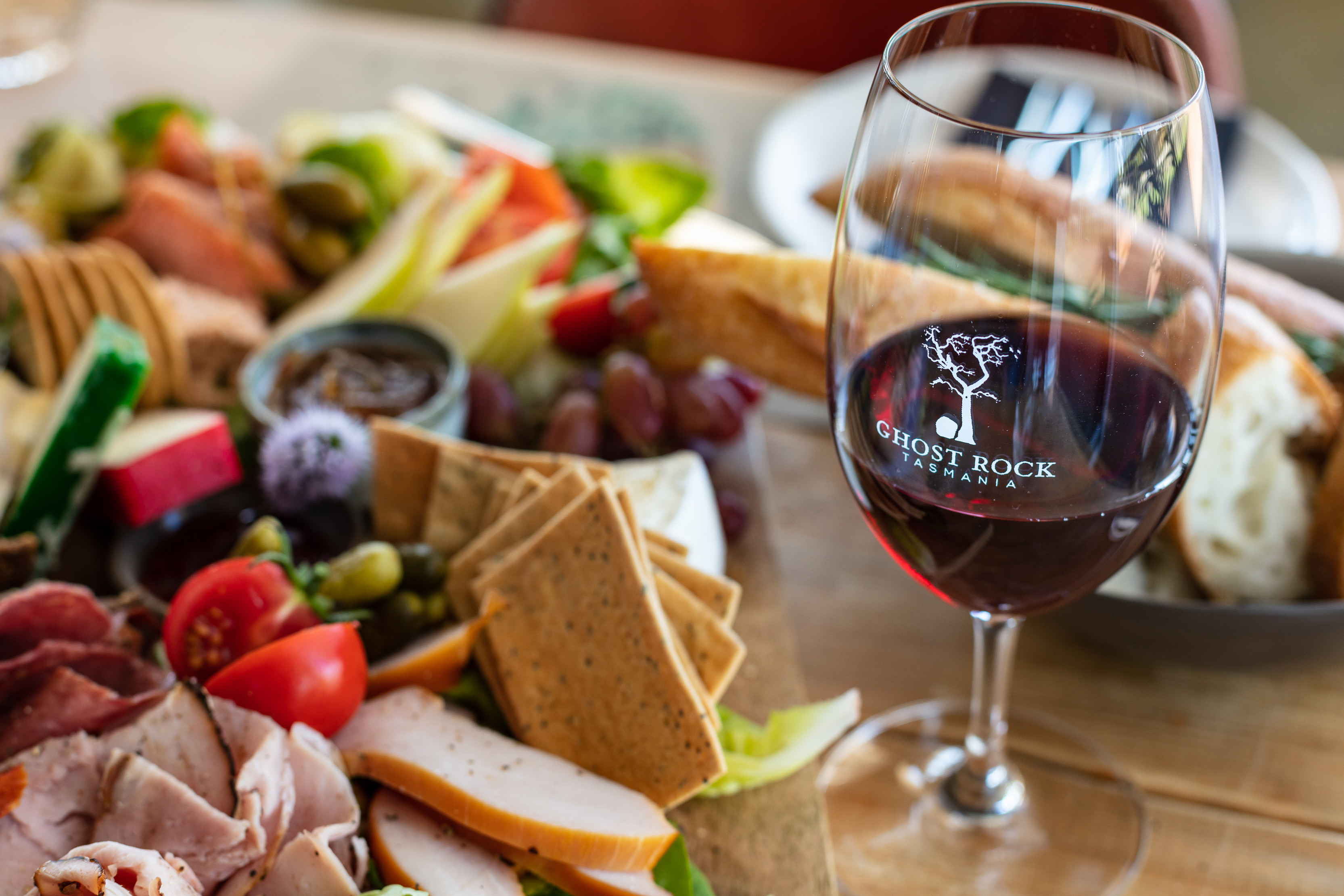 A vibrant, close up image of a platter with a variety of fresh food and red wine.