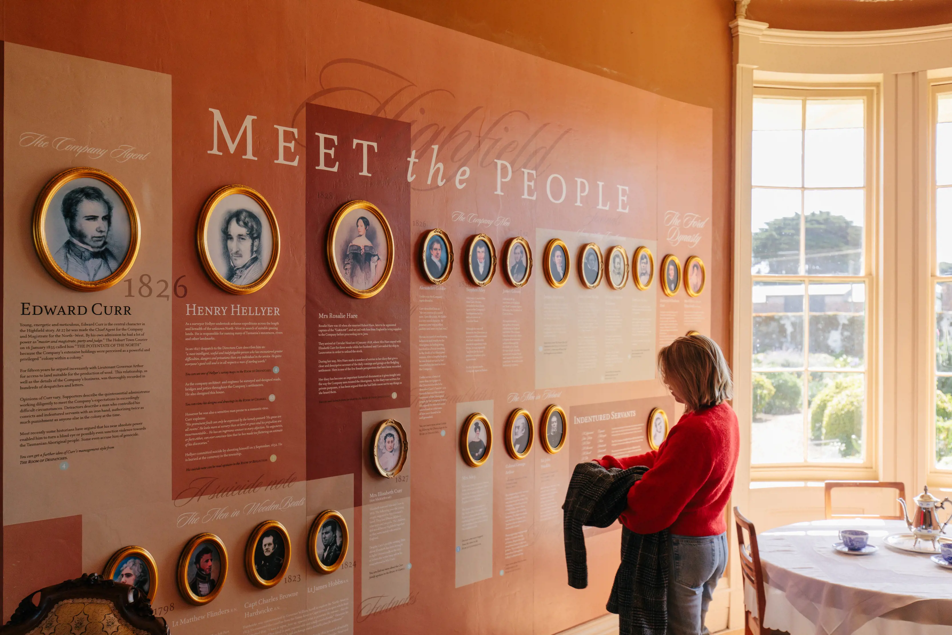 A lady reads information on the history of the Highfield Historic Site, on a wall that is within the Highfield Historic Site.