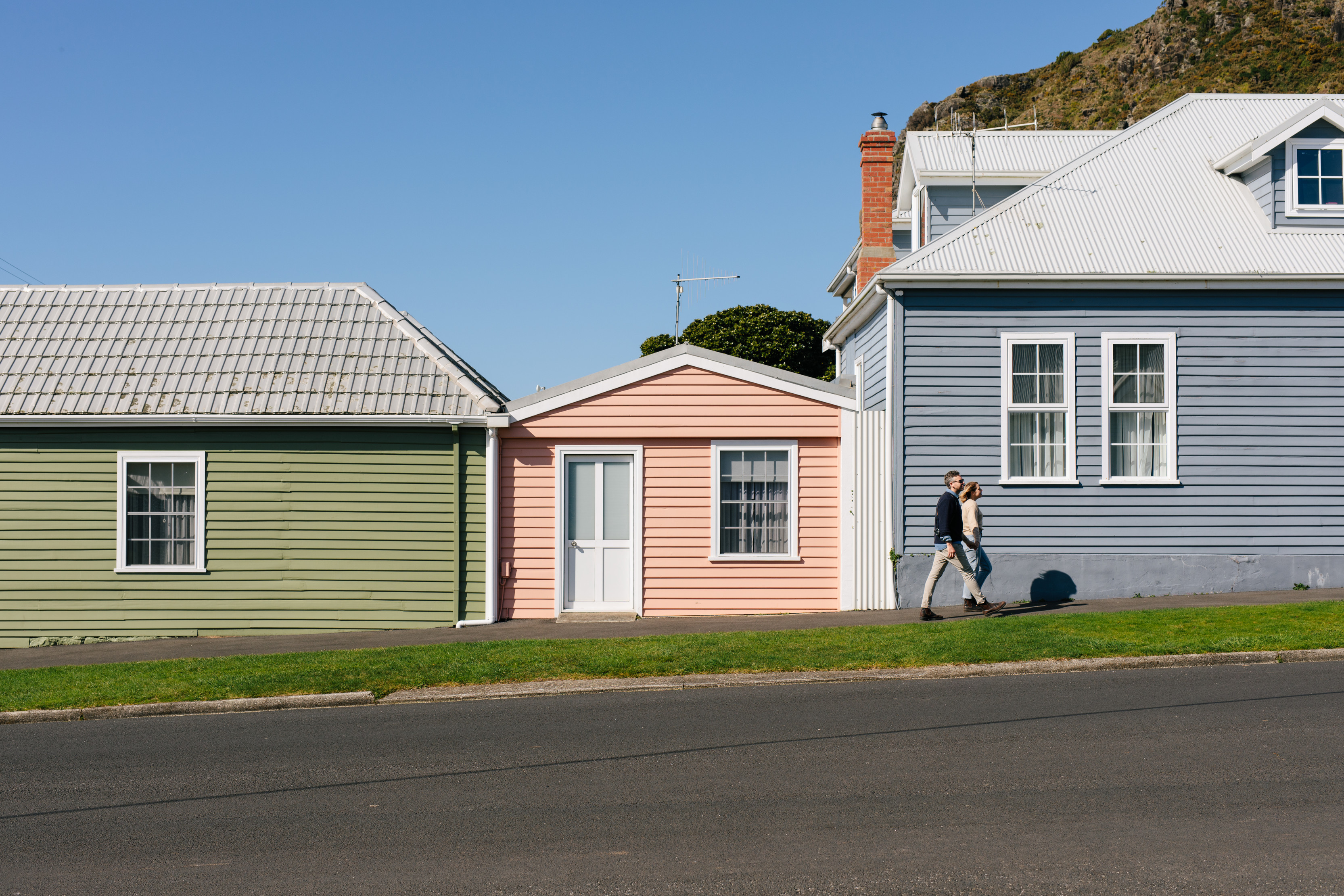 Image of a couple walking past three vibrant coloured cottages. 