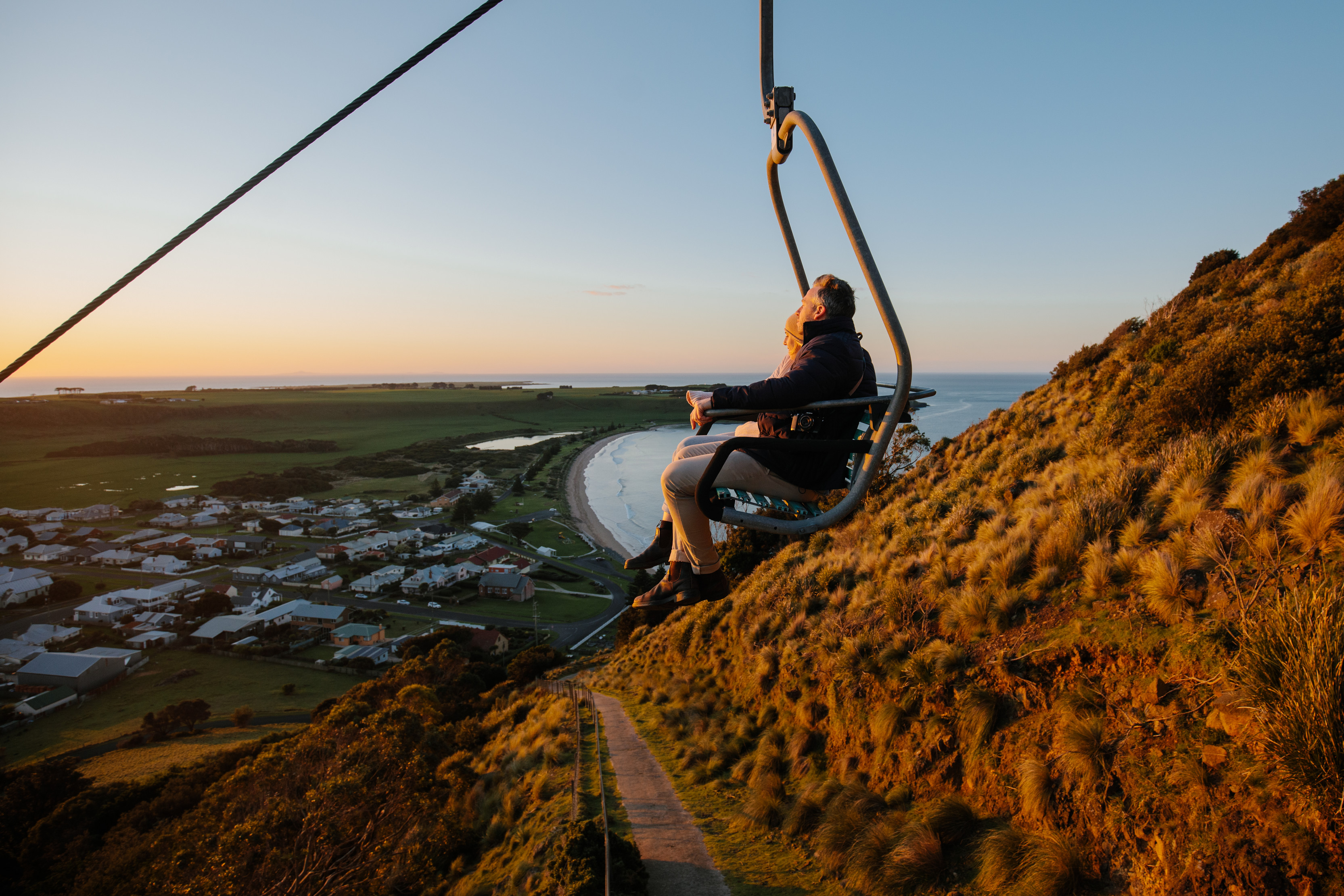 A couple sitting on The Nut Chairlift, overlooking the breathtaking views Stanley village, during an incredible sunrise.