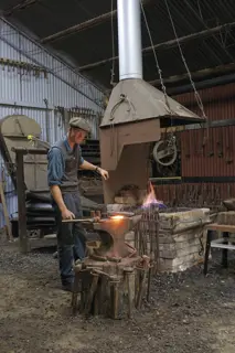 A blacksmith at work at Blacksmith Shop - West Coast Heritage Centre.