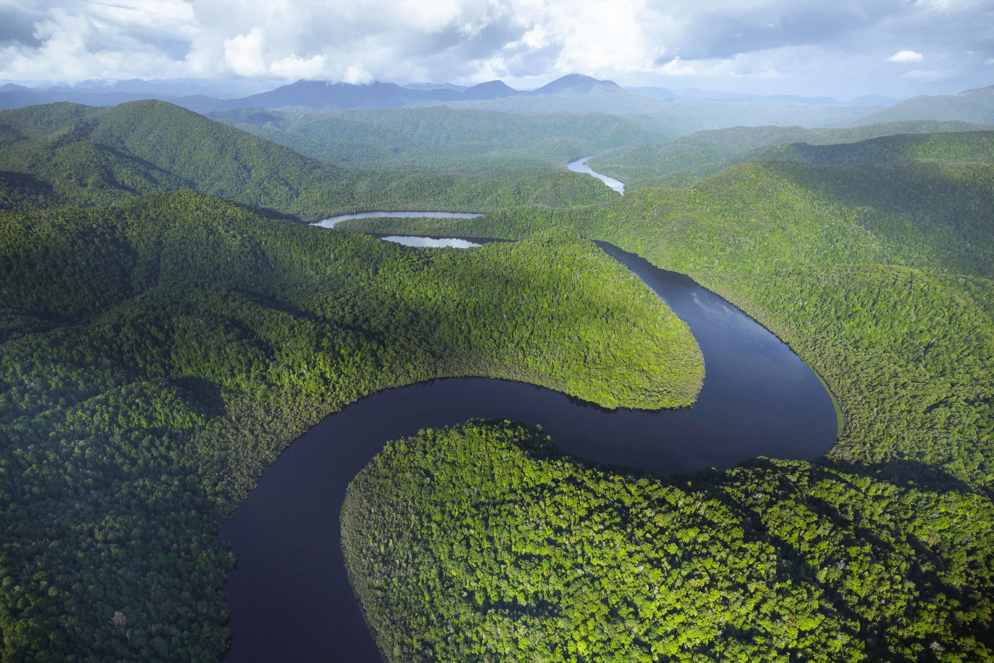 Breathtaking aerial shot of the Gordon river weaving through hills and vibrant green forests.