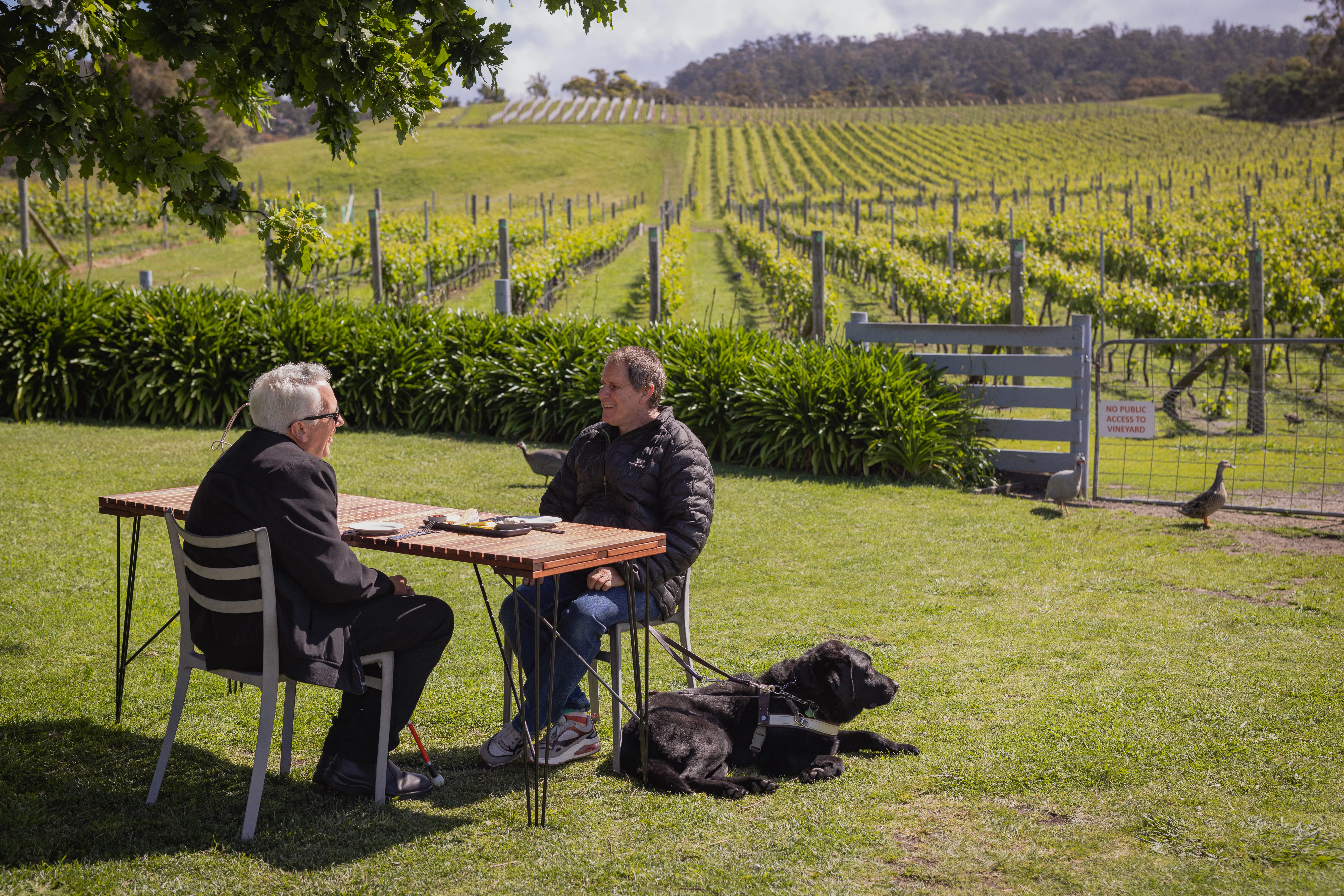Two men with their guide dog at the Puddleduck Vineyard.